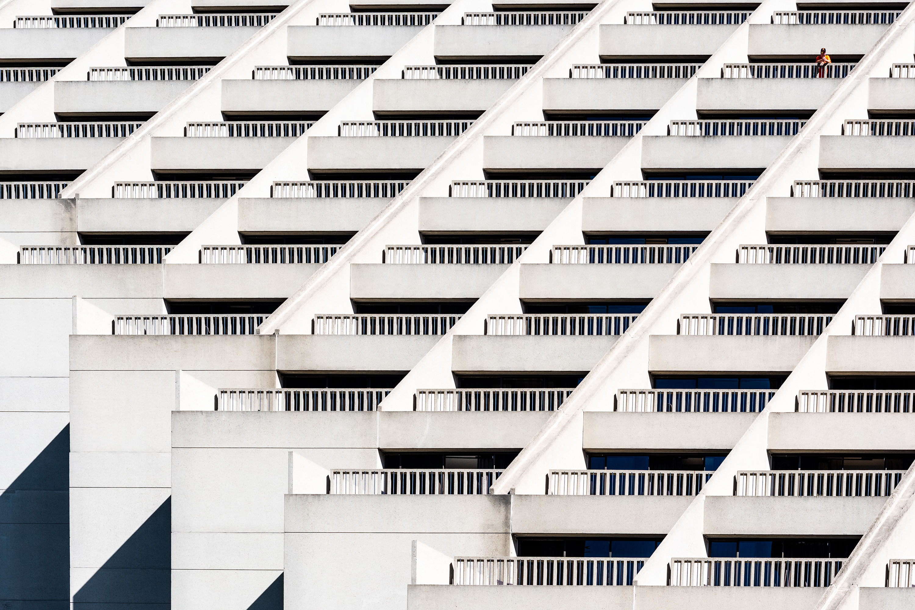 Graphical and close-up photography of a white building in San Fransisco. And man is standing on his balcony, looking down the street.