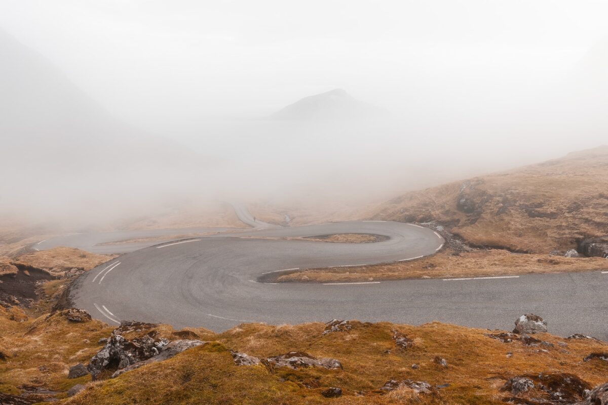 Winding road of Norðradalur in dense fog, Faroe Islands, with soft minimal landscape and hidden mountains