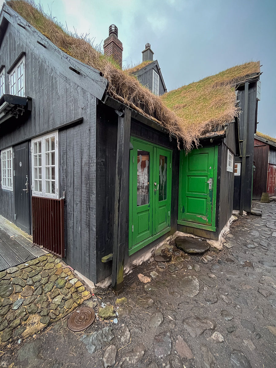 This captivating image showcases a quintessential scene in Tórshavn, the capital of the Faroe Islands—an iconic old house adorned with a charming grass-covered roof.
