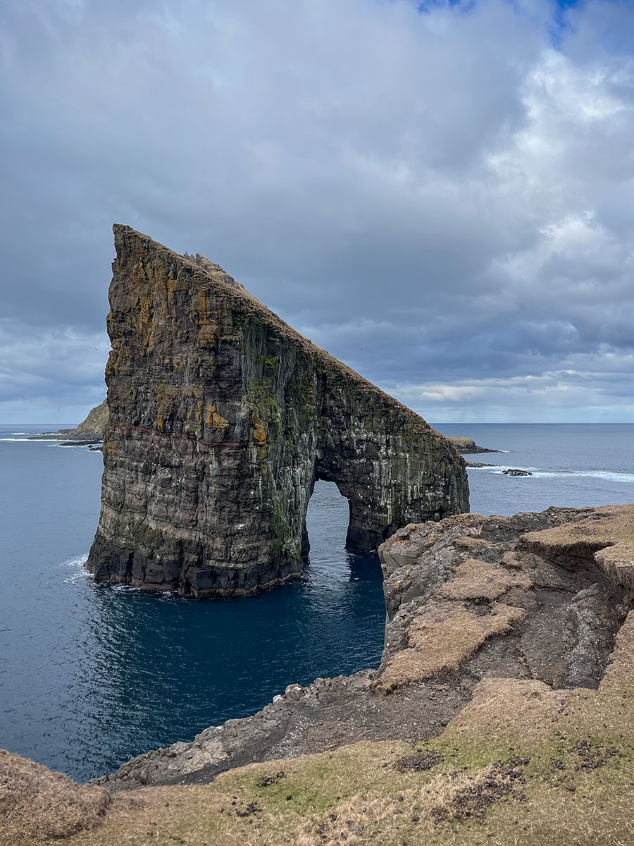 This striking image captures the ethereal beauty of the Drangarnir Sea Arch, a natural marvel in the Faroe Islands. The photograph frames the iconic sea arch, sculpted by the relentless forces of wind and waves against the rugged cliffs.