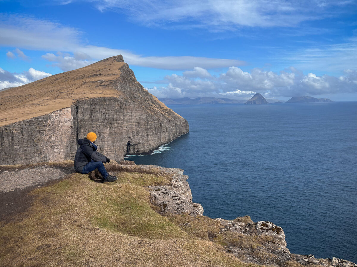This breathtaking landscape photograph captures the awe-inspiring panorama from Trælanípa cliffs, offering a mesmerizing view over the Faroe Islands. The rugged cliffs frame the scene, providing a dramatic foreground as the viewer's gaze extends over the vast expanse of the North Atlantic Ocean. The dynamic play of light and shadow highlights the undulating green hills and deep fjords of the Faroe archipelago. Clouds dance across the sky, casting fleeting shadows on the land below. This stunning composition from Trælanípa not only showcases the raw and untamed beauty of the Faroe Islands but also serves as a testament to the unparalleled artistry of nature in this remote and enchanting corner of the world.