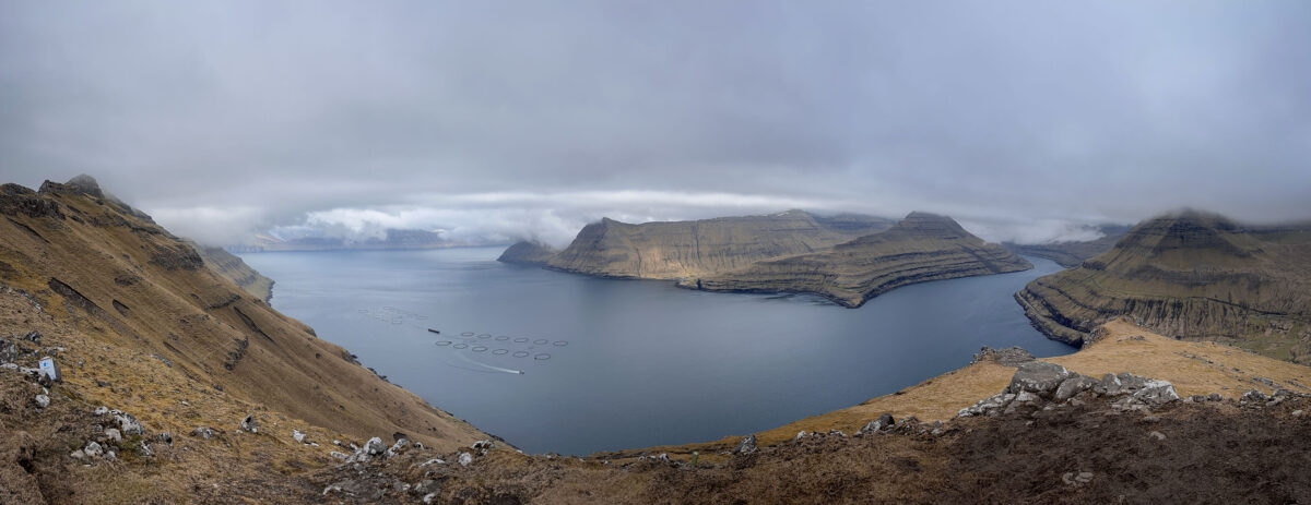 This mesmerizing panorama captures the expansive view from the Hvíthamar Trailhead, unveiling the breathtaking landscape of the Faroe Islands. The lens sweeps across the horizon, revealing a vast expanse of rolling hills, dramatic cliffs, and the boundless North Atlantic Ocean.