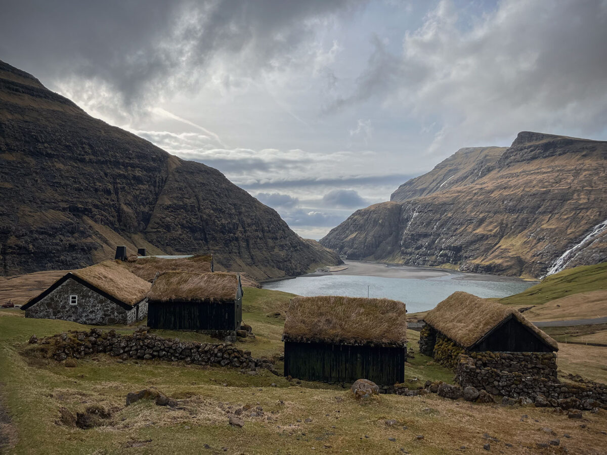 This image captures the quaint charm of Saksun village in the Faroe Islands, where traditional grass-roofed houses dot the picturesque landscape.