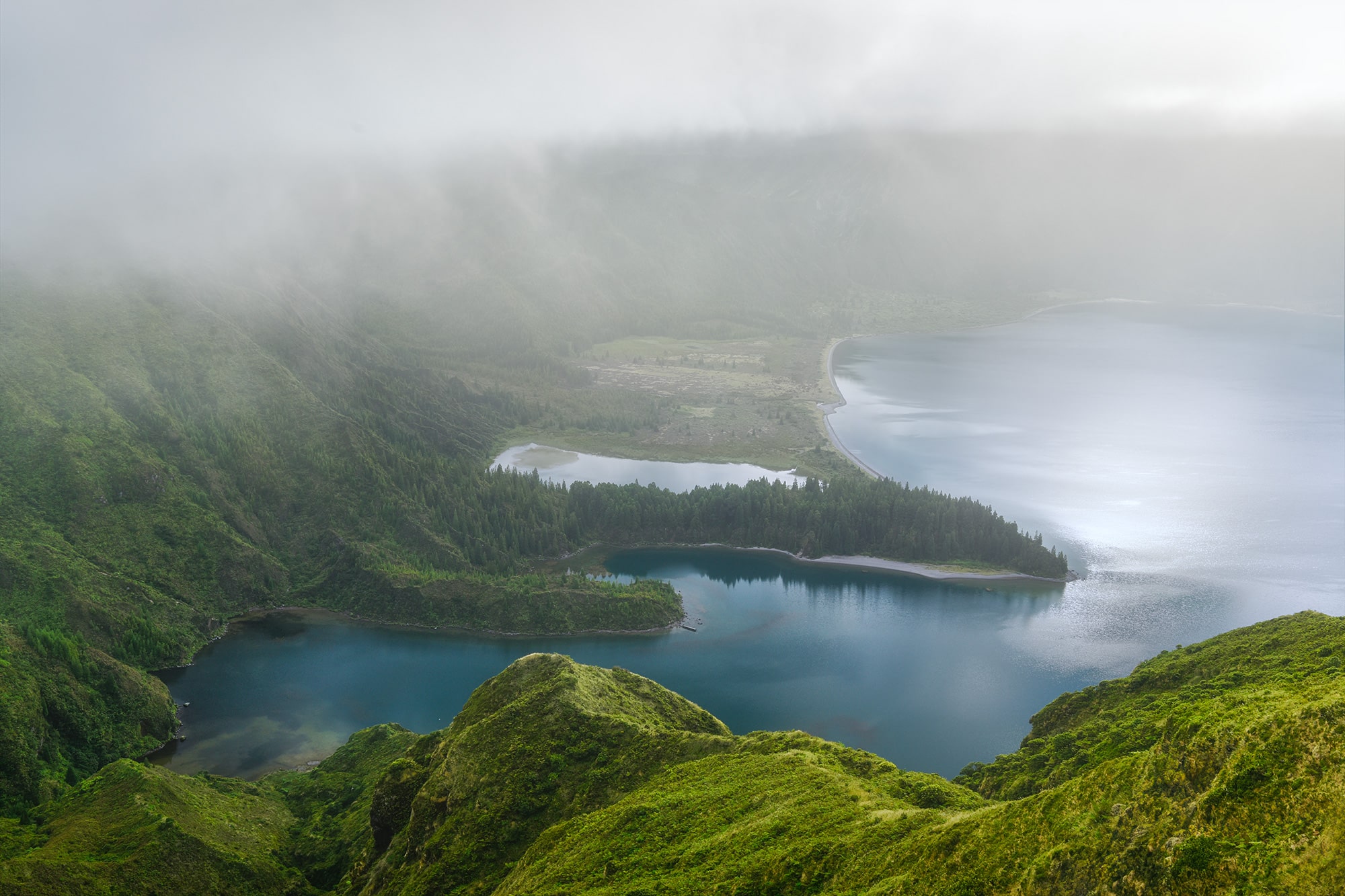 Behold the mesmerizing beauty of Lago do Fogo in São Miguel, captured through the lens of Jennifer Esseiva and her Nikon D810. This epic landscape photography showcases a foggy sunrise over the tranquil waters, enveloping the scene in an ethereal mist. Despite the raining morning, the serene ambiance of the lake remains undisturbed, offering a captivating view of nature's serene allure. Join Esseiva on this visual journey through São Miguel's breathtaking vistas, where every frame tells a story of the island's timeless charm and natural splendor.