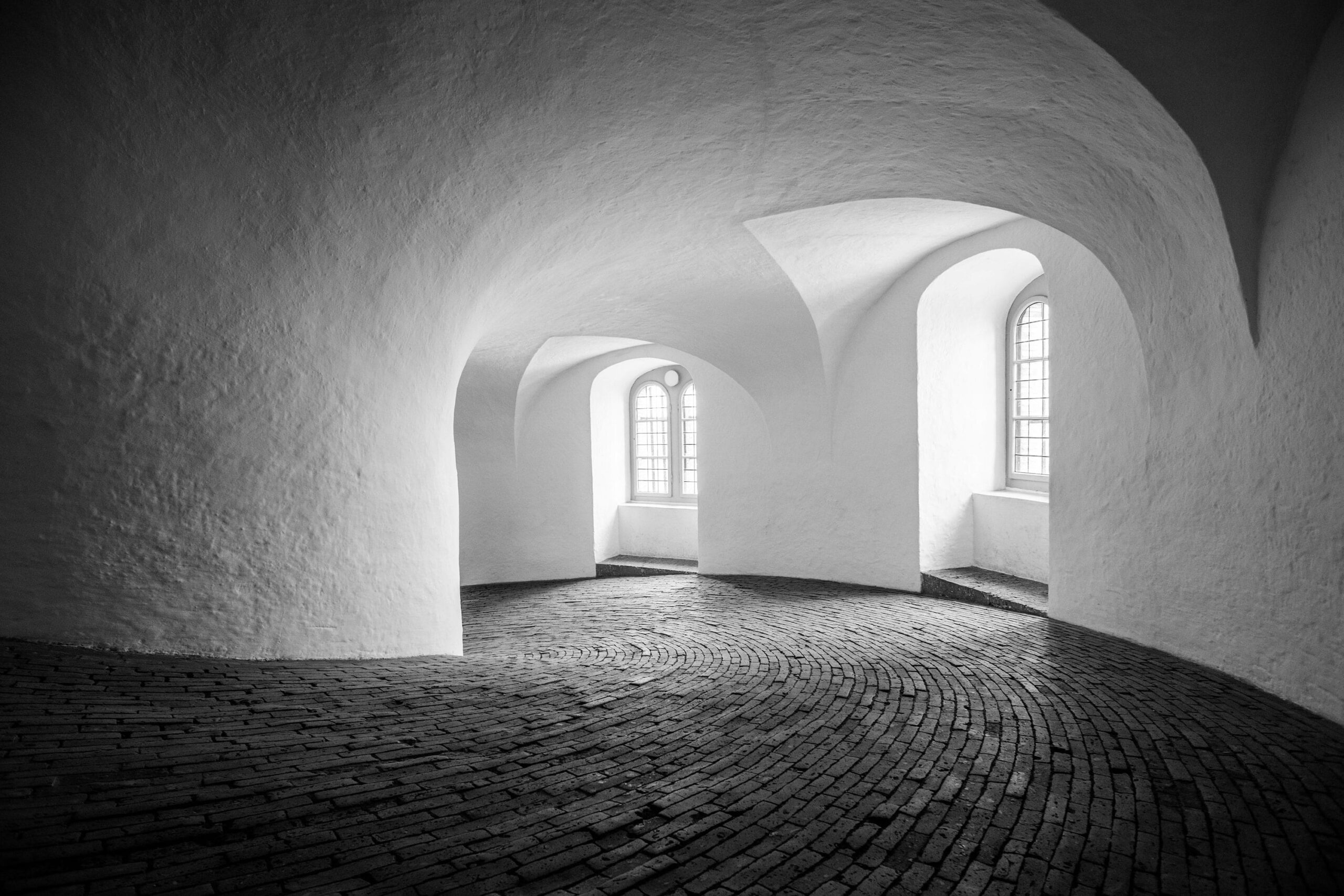 Monochrome image showcasing the interior of Rundetaarn in Copenhagen, Denmark. The winding path leading upwards is captured in minimalist black and white, emphasizing the architectural elegance of the historic tower. Photographed by travel photographer Jennifer Esseiva using her Nikon D810, this image epitomizes the beauty of simplicity and evokes a sense of timeless charm.