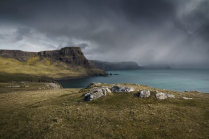 Rainstorm over Waterstein Head near Neist Point, Isle of Skye, Scotland, with dramatic clouds and rugged cliffs.