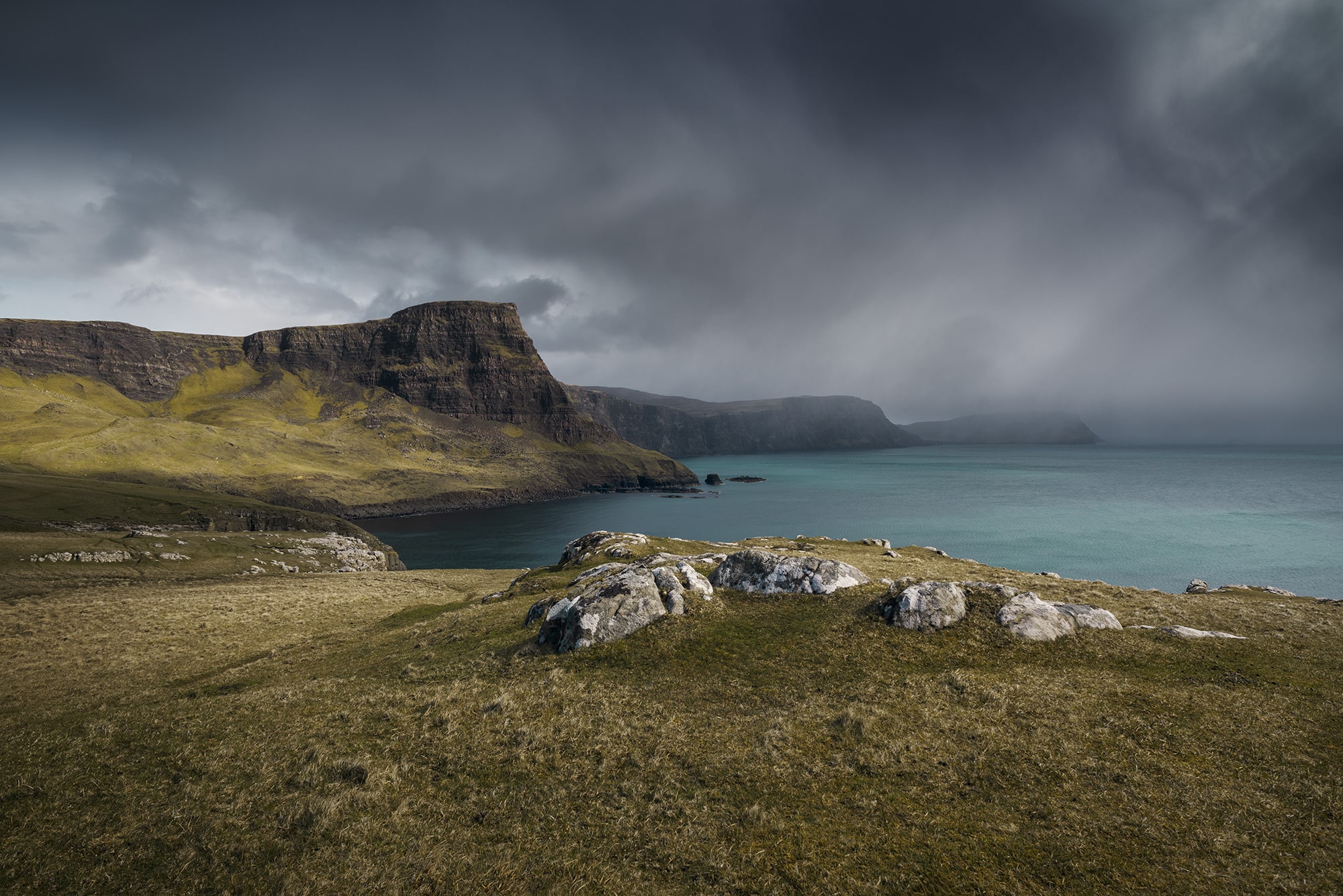 Immerse yourself in the rugged beauty of Skye Island, Scotland, with this captivating landscape photography captured by Swiss photographer Jennifer Esseiva and her Nikon D810. Behold the dramatic scene of a rainstorm sweeping over Waterstein Head, near the iconic Neist Point, as captured through Jennifer Esseiva's lens. The tumultuous skies and swirling clouds create a sense of raw energy and untamed beauty, while the rugged cliffs of Skye Island stand resilient against the elements. Join Esseiva on this visual journey through the Scottish Highlands, where every frame captures the timeless drama and majesty of nature's power.