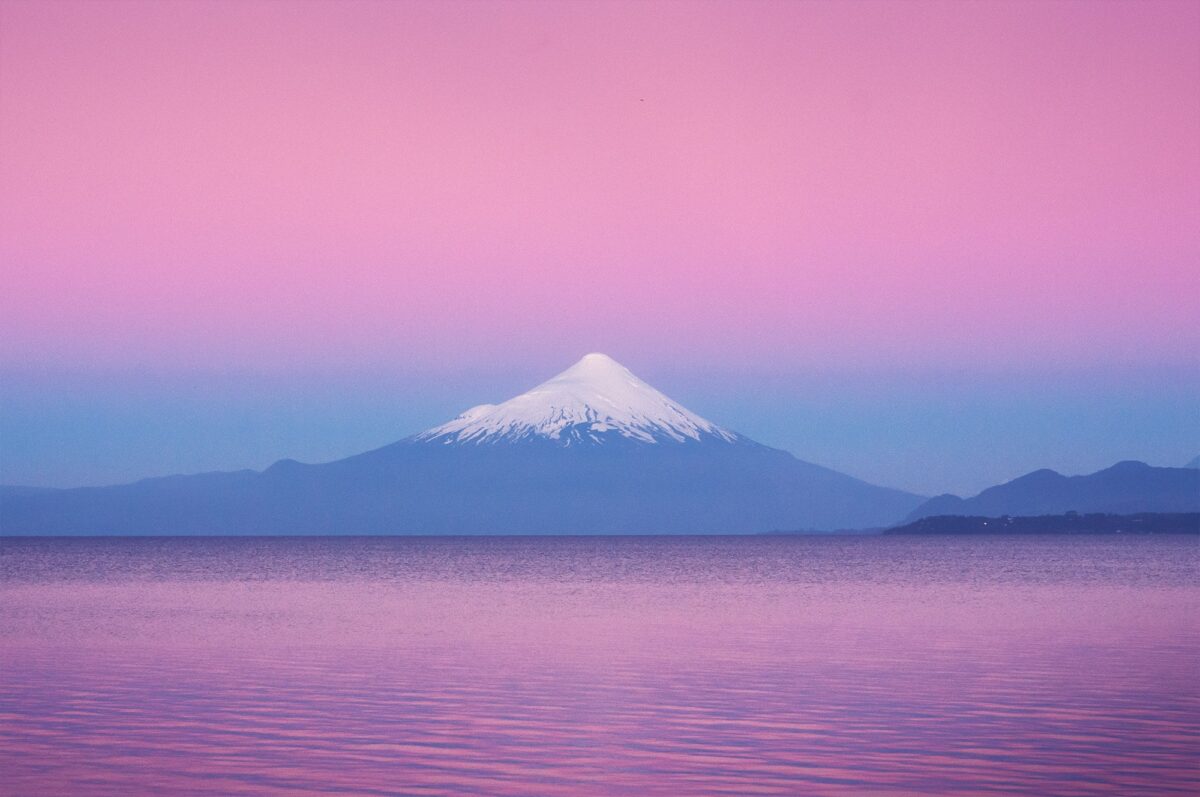 Osorno Volcano at sunset near Puerto Varas, Chile, under a pink sky with dramatic mountain silhouette.