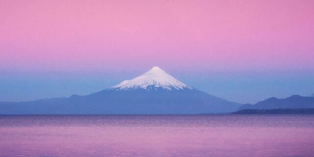 Journey into the captivating world of landscape photography with this stunning image of the Osorno Volcano at a breathtaking pink sky sunset in Puerto Varas, Chile. Skillfully captured by renowned Swiss photographer Jennifer Esseiva, this mesmerizing photograph showcases the iconic silhouette of the Osorno volcano against the vibrant hues of the evening sky. Immerse yourself in the natural beauty of this Chilean gem as captured through Esseiva's lens, revealing the picturesque charm of Puerto Varas. Experience the magic of the golden hour with the expertly composed and visually striking portrayal of the Osorno volcano, beautifully rendered in this exquisite sunset scene by Jennifer Esseiva, a master of her craft.