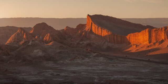 Sunset over Valle de la Luna near San Pedro de Atacama, Chile, with dramatic desert silhouettes and warm evening light.