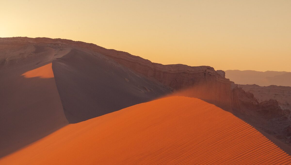 Sunset from a sand dune near San Pedro de Atacama, Chile, with wind-shaped textures and warm desert light.