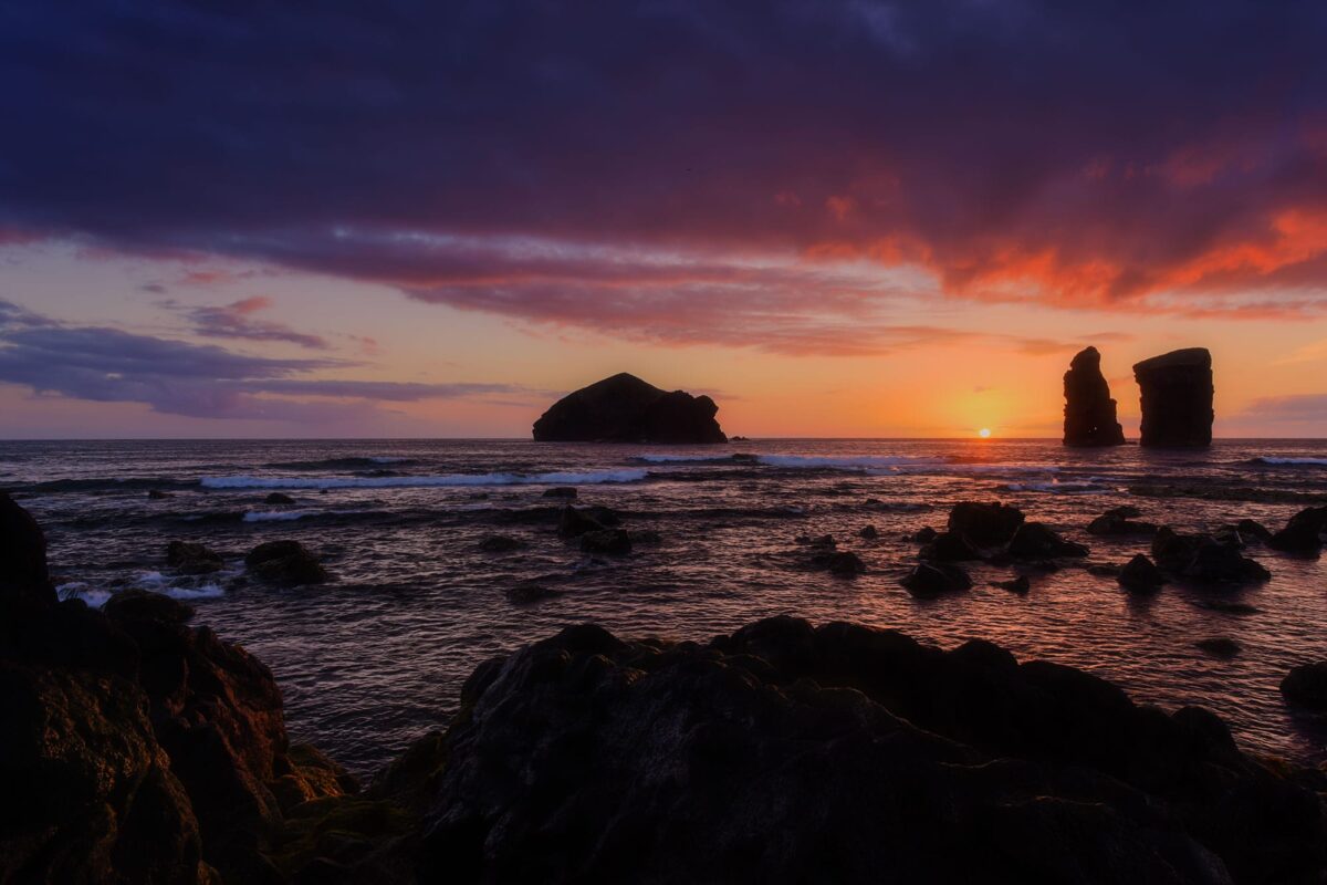 Sunset at Praia dos Mosteiros, São Miguel, Azores, with pink and golden sky over volcanic coastline.