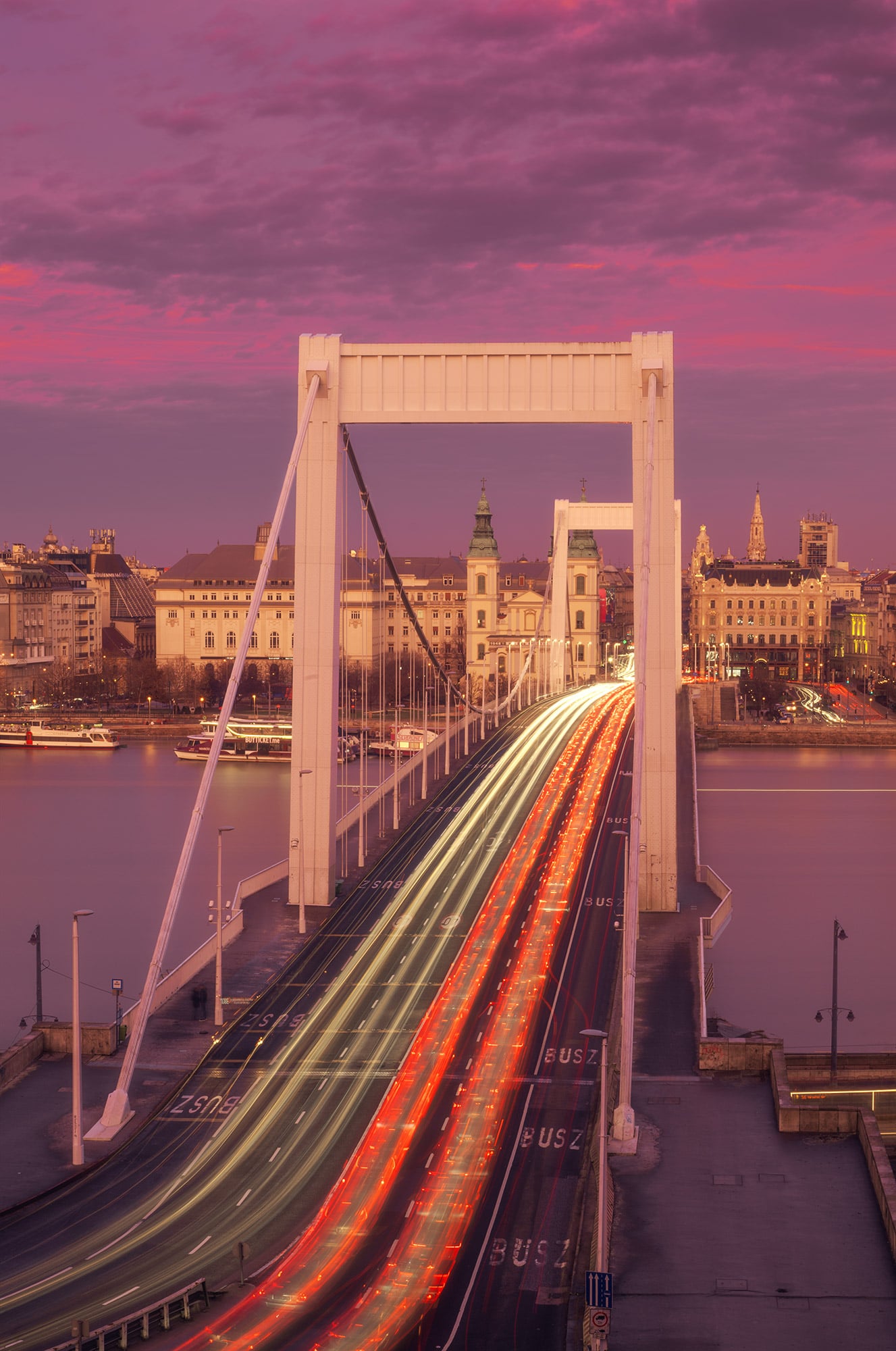 Behold the majestic Elizabeth Bridge in Budapest, captured in vertical photography at sunset by travel photographer Jennifer Esseiva using her Nikon Z8. The warm hues of the setting sun cast a golden glow over the iconic bridge, illuminating the cityscape with a captivating brilliance. From the intricate architectural details to the tranquil waters of the Danube River below, this stunning image encapsulates the timeless beauty and allure of Budapest's skyline. Immerse yourself in the breathtaking panorama of the Hungarian capital through Jennifer Esseiva's lens, and experience the magic of sunset over the Elizabeth Bridge.