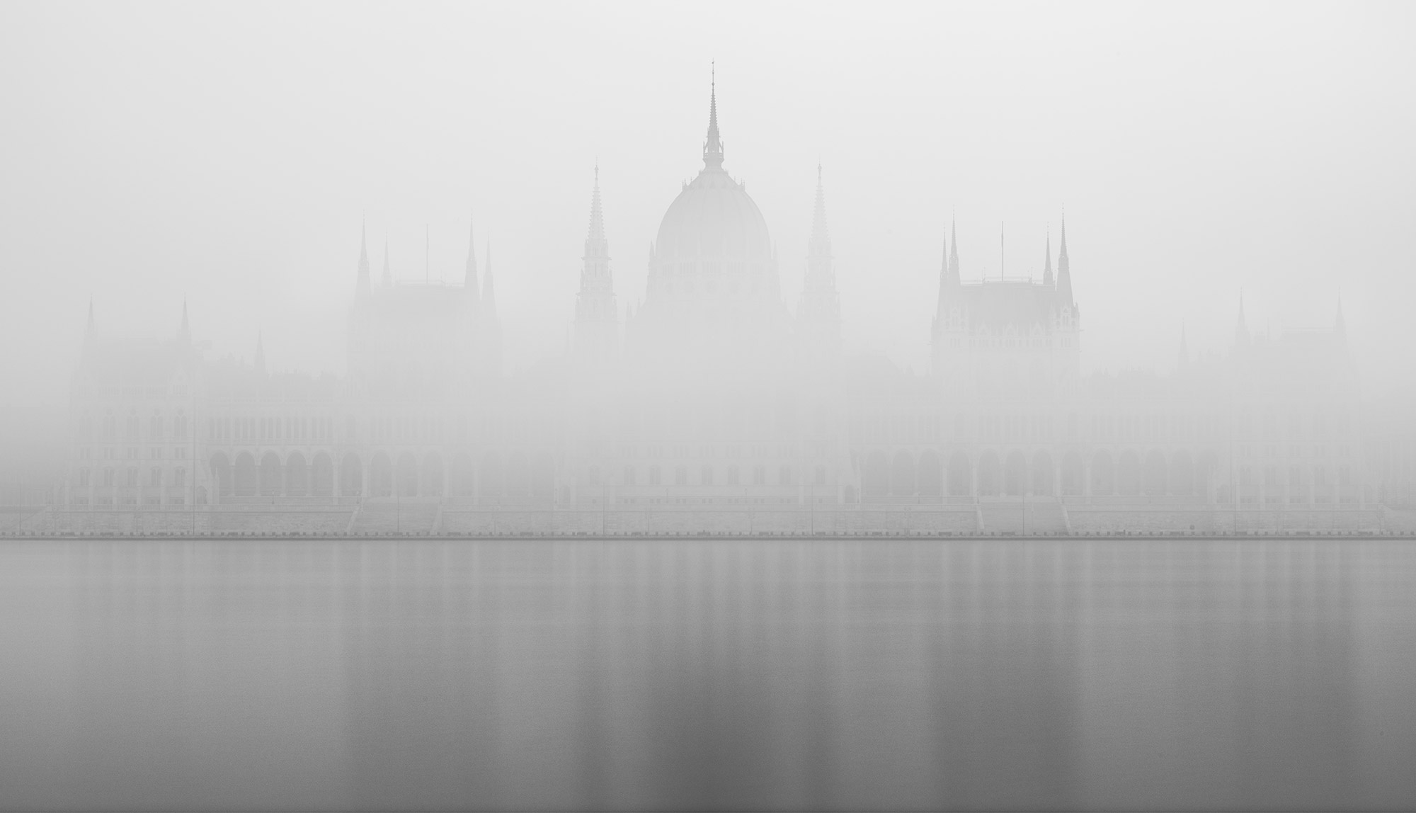 Experience the ethereal beauty of Budapest's Parliament enveloped in dense fog in this captivating long exposure photograph by travel photographer Jennifer Esseiva, captured with her Nikon Z8. The iconic silhouette of the Parliament building emerges mysteriously from the mist, creating a hauntingly beautiful scene. With expert composition and skilled use of long exposure techniques, Jennifer Esseiva brings to life the enchanting ambiance of Budapest's skyline shrouded in fog. Immerse yourself in the atmospheric allure of this unique perspective on the Parliament, captured with precision and artistry.