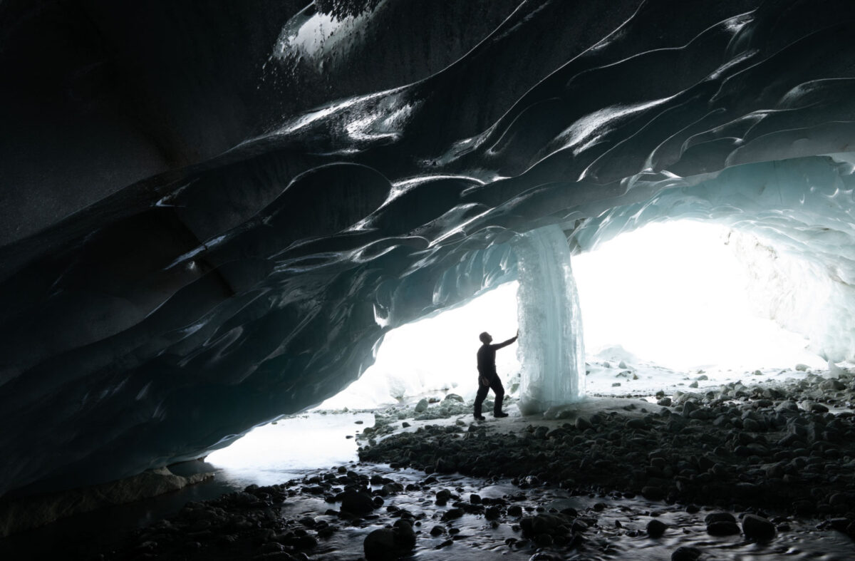 The latest addition to my panoramic masterpiece captures a moment of wonder as my friend reaches out to touch the ice waterfall within the majestic ice cave.