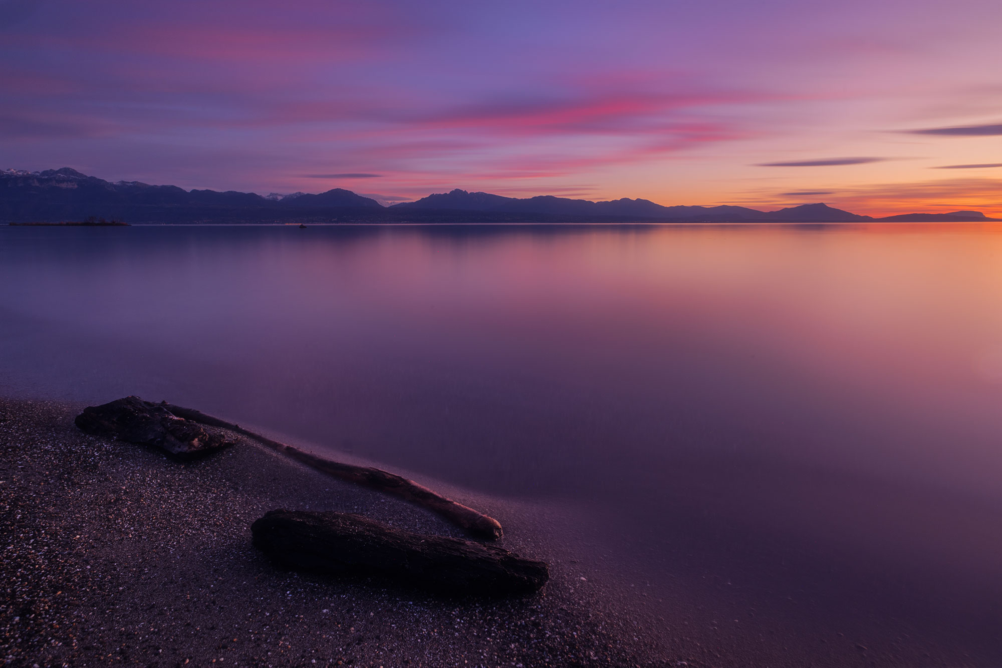 Embark on a visual odyssey through the lens of renowned Swiss photographer Jennifer Esseiva, capturing the breathtaking beauty of a pink sunset over Lake Geneva from Préverenges Beach. With a mastery of long exposures, Jennifer crafts a mesmerizing scene where the tranquil waters reflect the hues of the twilight sky. Immerse yourself in the artistry of Swiss landscape photography, as every frame transports you to the serene shores of Lake Geneva, Switzerland.