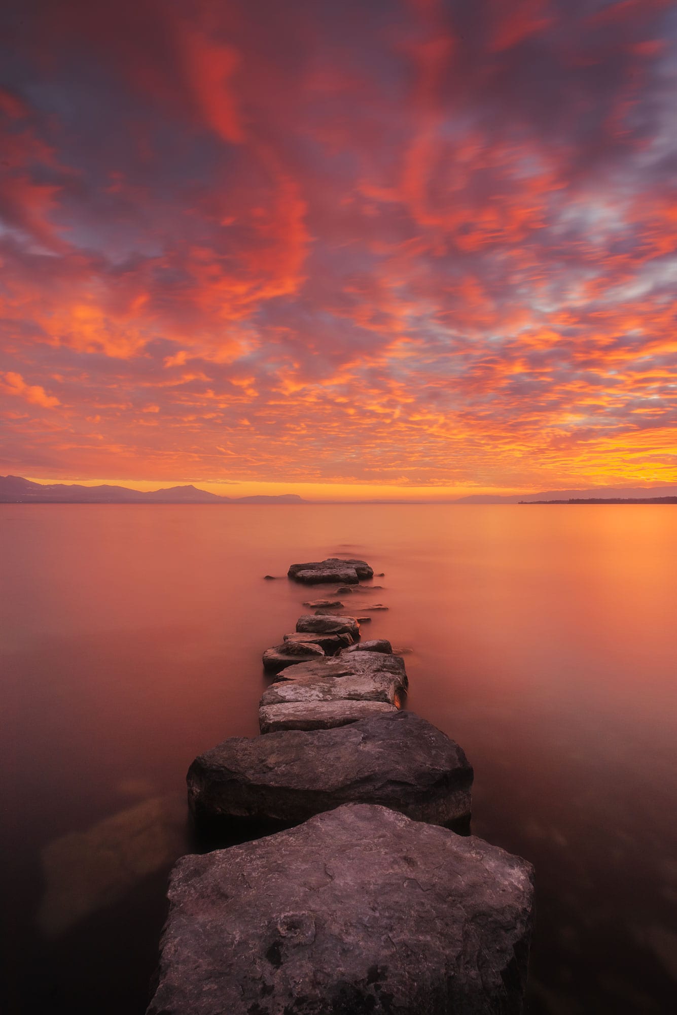Indulge in the captivating beauty of a fiery red sunset captured through the lens of landscape photographer Jennifer Esseiva. This stunning landscape photograph, taken at Préverenges Beach in Canton Vaud, Switzerland, unveils the vibrant hues of the setting sun over the serene waters of Lake Geneva. Immerse yourself in the dramatic allure of this red sunset, expertly framed to showcase the enchanting landscapes of Switzerland.
