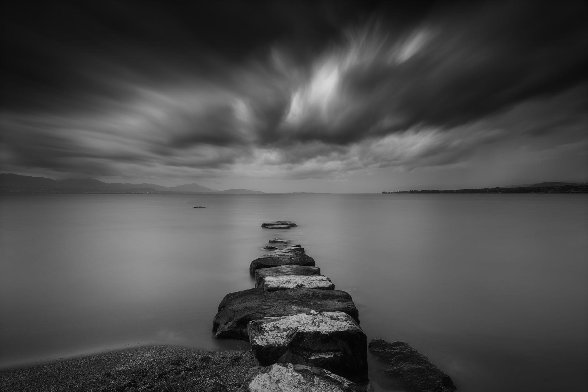Dive into the captivating world of long exposure black and white photography through the lens of Swiss photographer Jennifer Esseiva. Witness the raw power of nature as she captures a tumultuous storm at Préverenges Beach, Lake Geneva. Each frame is a masterclass in landscape photography, revealing the dramatic interplay between light and shadow in this mesmerizing monochrome composition. Experience the dynamic beauty of Switzerland in the throes of a storm, expertly captured by Jennifer's lens.