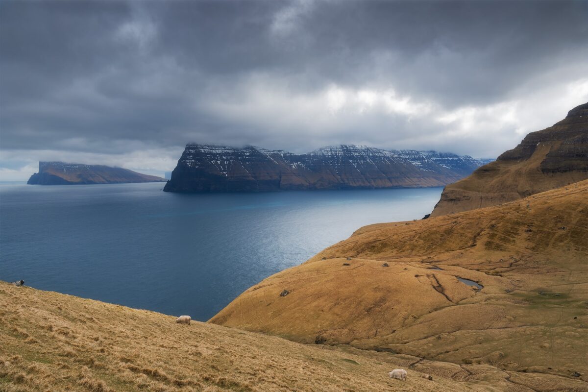 Kalsoy Island under dark dramatic sky in the Faroe Islands, with rugged cliffs and ocean landscape.