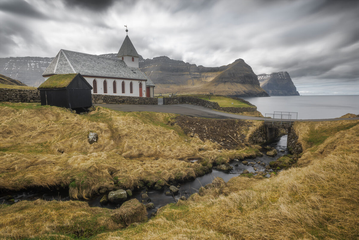 Viðareiði Church on Viðoy Island, Faroe Islands, in long exposure with rugged coastal landscape.