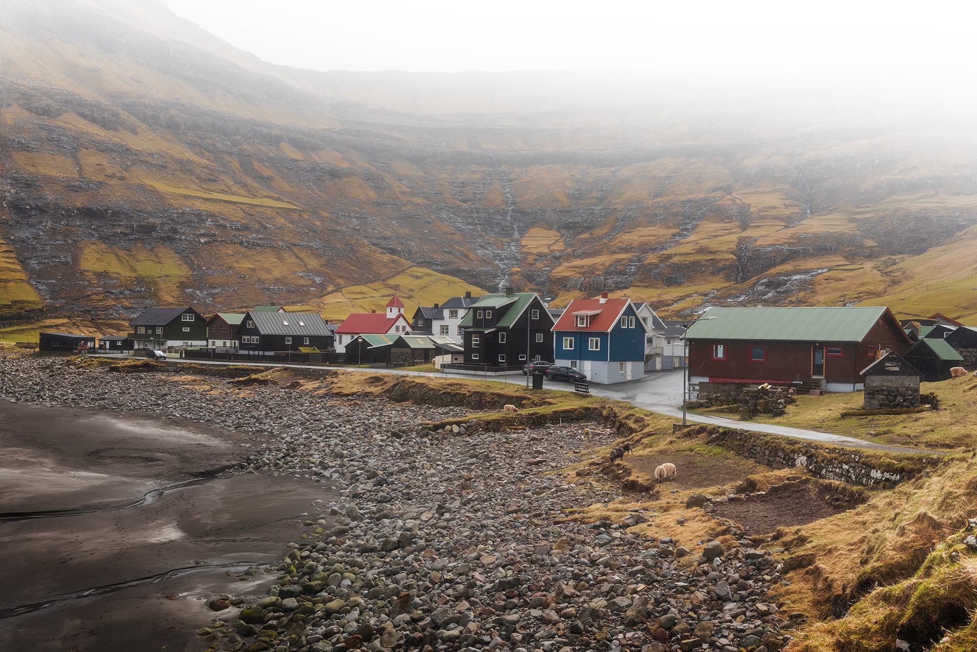 Experience the enchanting allure of landscape photography with this captivating image capturing the village of Tjørnuvík immersed in a moody atmosphere in the Faroe Islands. Delve into the mystical ambiance as the rugged terrain and quaint houses evoke a sense of timeless charm against the backdrop of dramatic skies. Let yourself be transported to this remote coastal village, where every corner holds a story waiting to be discovered.