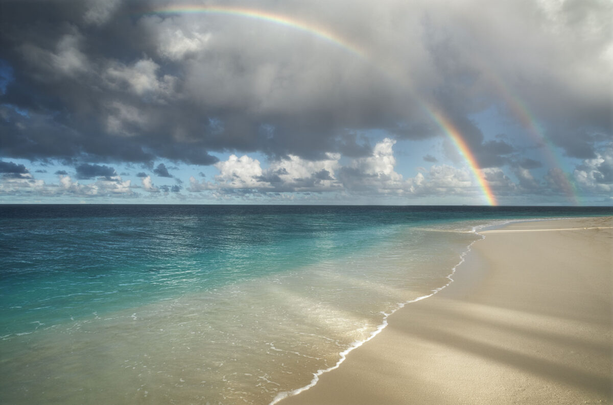 Beach at Thudufushi Resort, Maldives, with double rainbow over turquoise lagoon and tropical shoreline