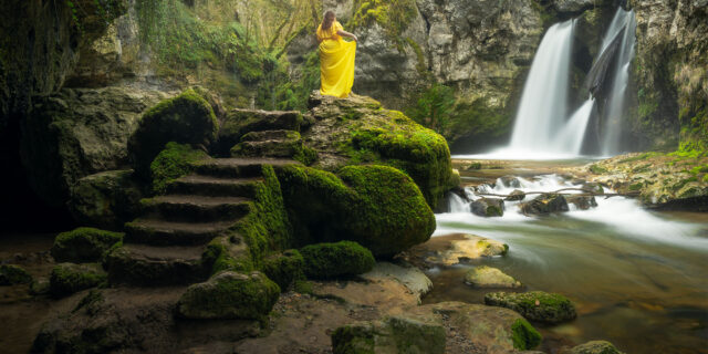 Explore the captivating world of landscape photography through the lens of Jennifer Esseiva, as she portrays herself amidst the natural splendor of the Swiss landscape. Adorned in a striking yellow dress, Jennifer embodies the essence of a forest nymph, standing gracefully atop the stairs overlooking the majestic Tine de Conflens waterfall near the village of Orbe in canton Vaud, Switzerland. This mesmerizing self-portrait, captured with her Nikon Z8, invites viewers to immerse themselves in the enchanting beauty of Switzerland's scenic wonders. Experience the magic of nature through Jennifer's lens in her landscape photography portfolio.