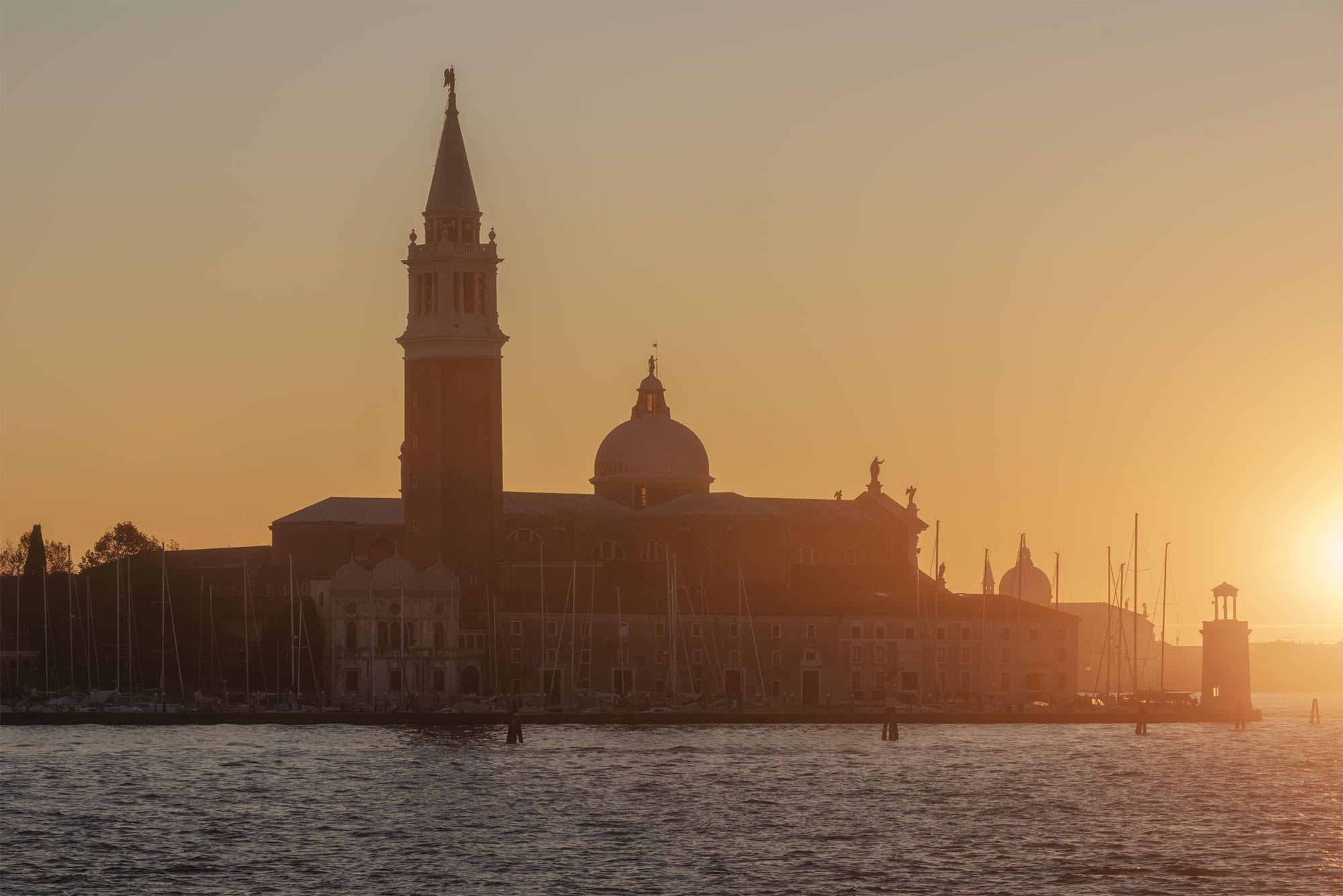 Landscape photography capturing a sunset at Campanile di San Giorgio Maggiore in Venice, Italy, during the golden hour.