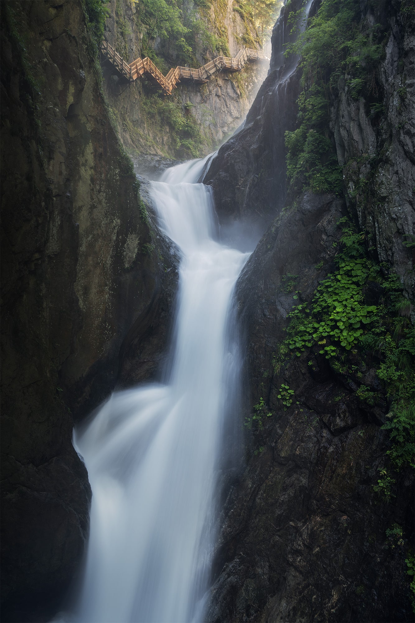 Long exposure shot of a fairytale waterfall cascading in the Gorges du Durnand, Bovernier, Valais, Switzerland. A set of stairs appears to lead to heaven above the waterfall. Captured with a Nikon Z8.