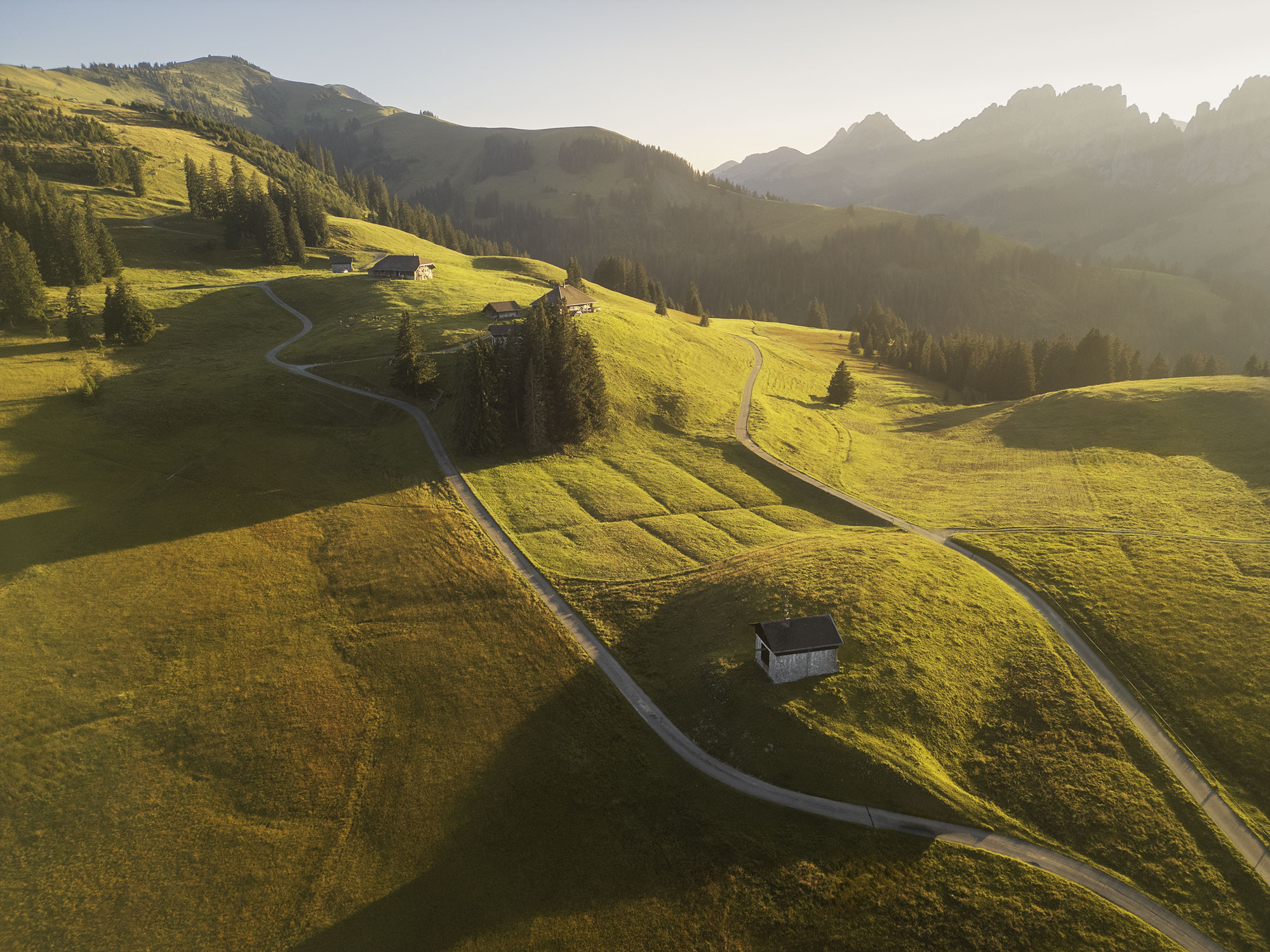 Aerial view of Gastlosen mountains from Jaunpass, Switzerland, during golden hour with warm light on rugged peaks.