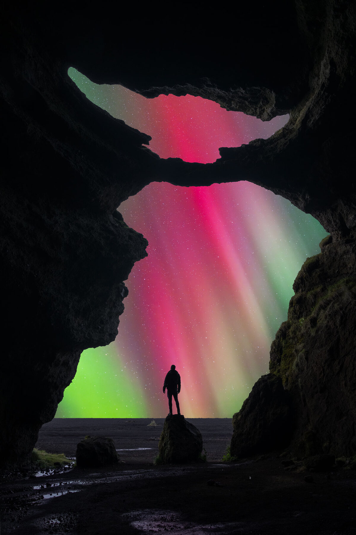 Northern lights at Yoda Cave, Iceland, with aurora illuminating cave opening and night sky.