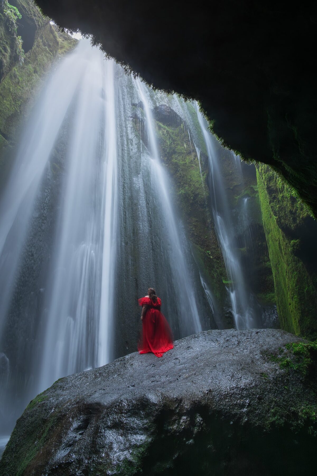Discover the art of self-portrait photography with Jennifer Esseiva, a talented landscape photographer. See her stunning capture at Gljúfrabúi waterfall in Iceland, featuring her in a striking red dress amidst the cascading falls.