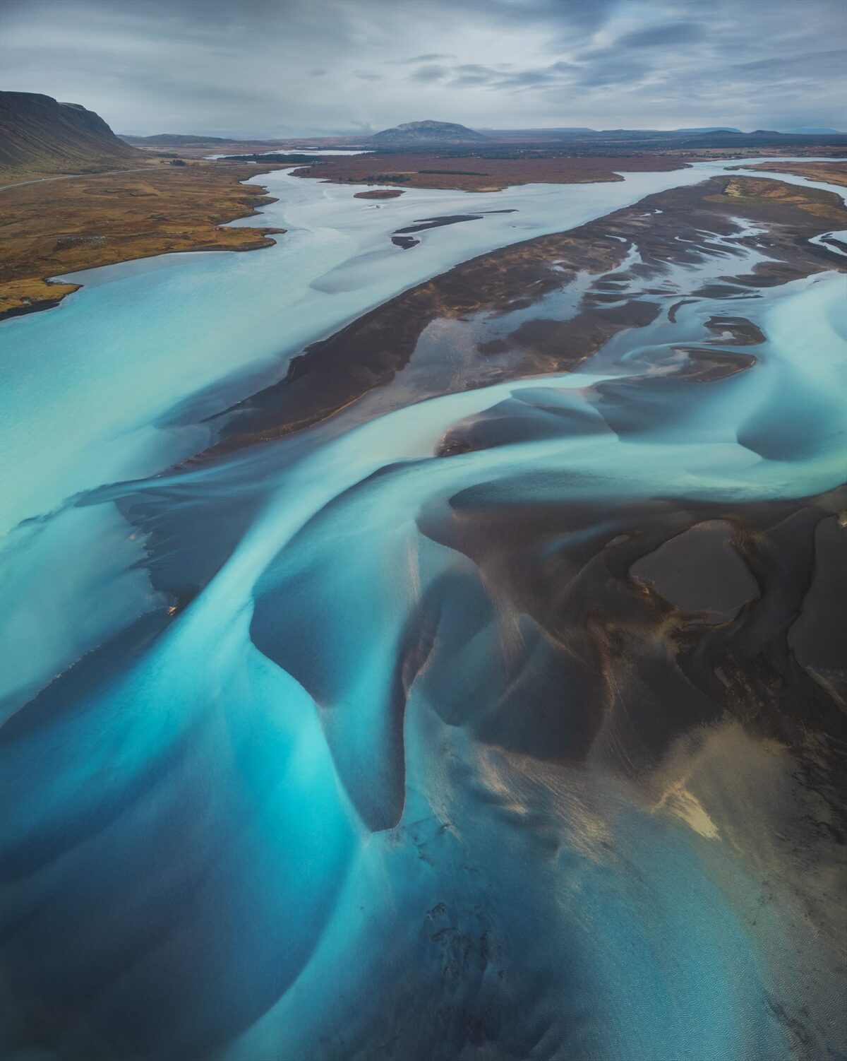 Drone photography in Iceland capturing a panoramic aerial view of braided rivers in South Iceland, highlighting abstract water patterns and volcanic textures.