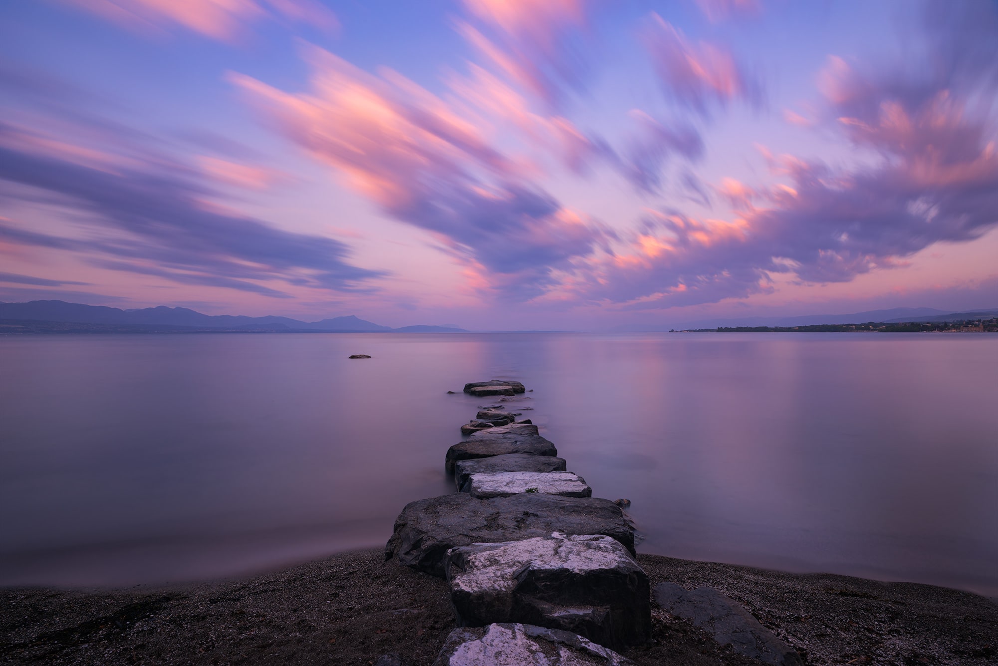 Epic sky landscape photography showing a beautiful sunset over Lake Geneva, captured from Préverenges beach near Lausanne, Switzerland.