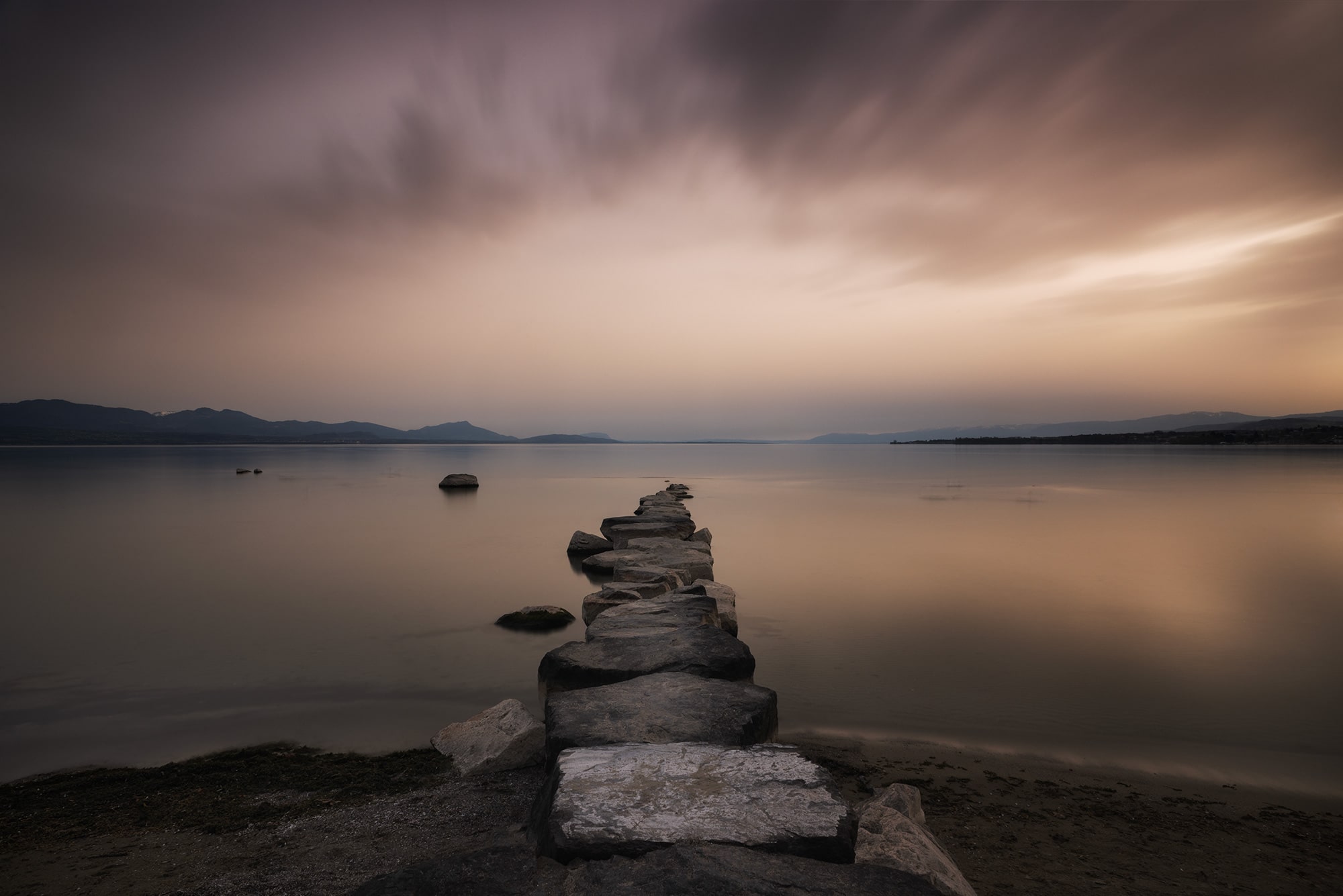Long exposure landscape photography of Préverenges beach at sunset, with Sahara dust in the atmosphere creating a surreal brown tint over Lake Geneva and the sky.