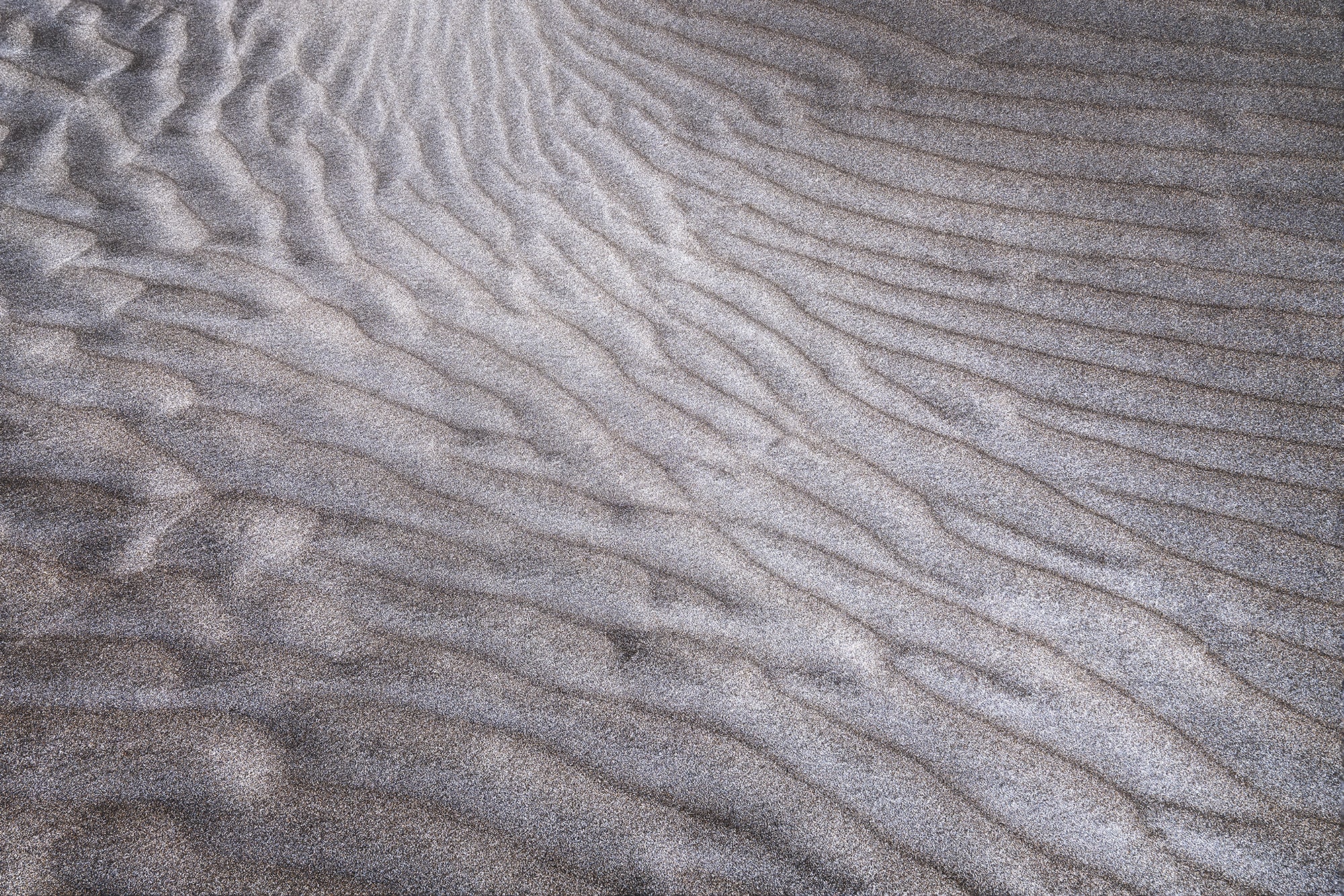 Abstract sand patterns shaped by the wind at the Famara Dunes in Lanzarote, Canary Islands, photographed by Swiss landscape photographer Jennifer Esseiva with a Nikon Z8.