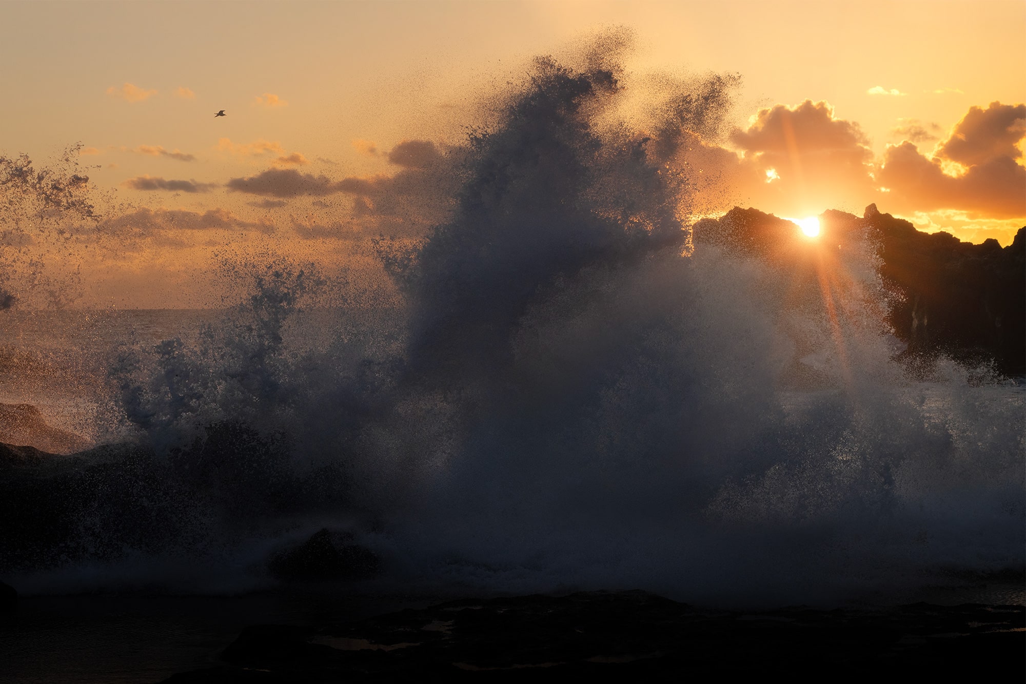 Sunset seascape at La Cresta del Dragón Colorao near El Golfo, Lanzarote. Large waves breaking against volcanic cliffs under glowing golden light.