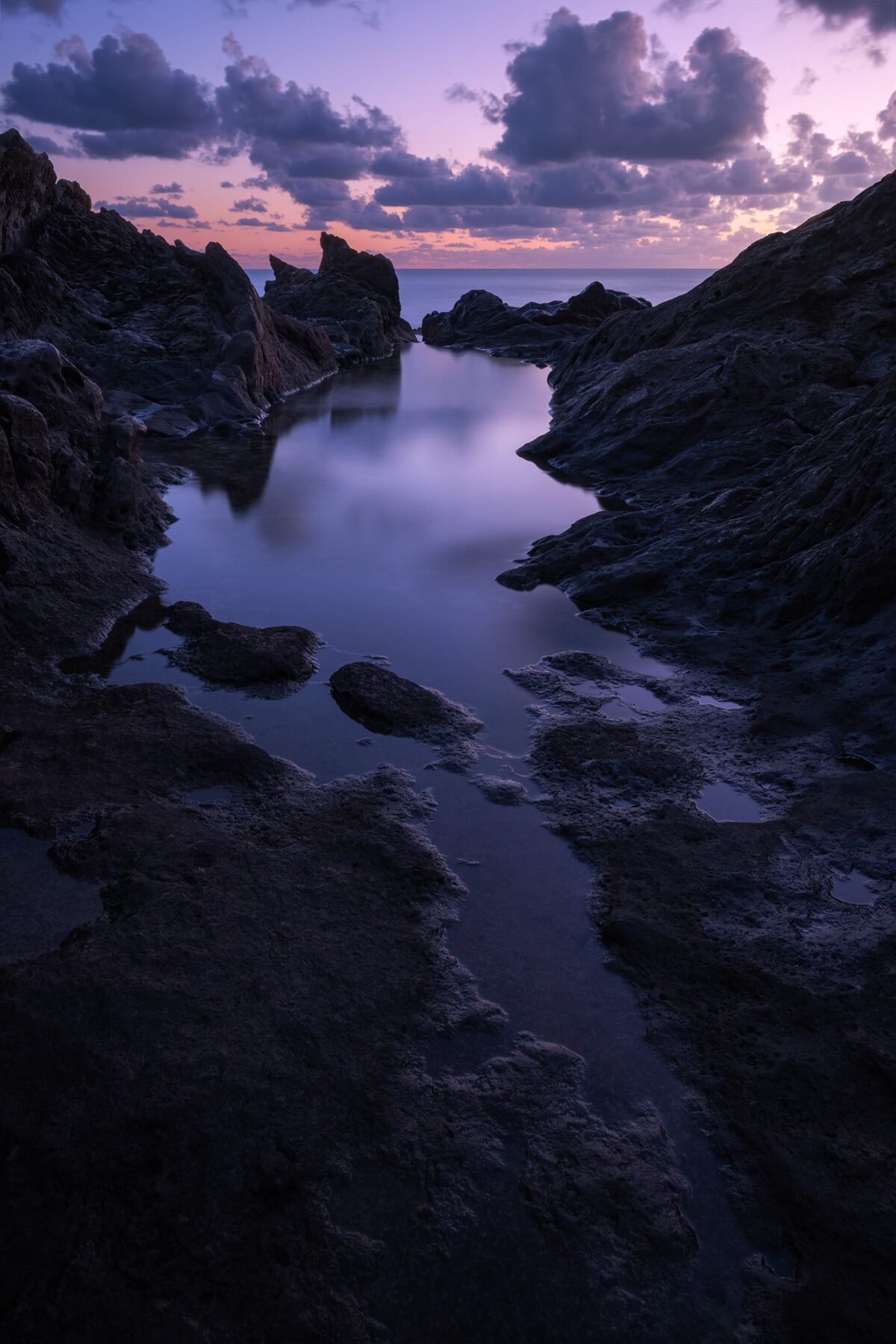 Blue hour long exposure of La Cresta del Dragón Colorao in Lanzarote, Canary Islands, featuring dark volcanic stones and soft twilight tones in a peaceful seascape.