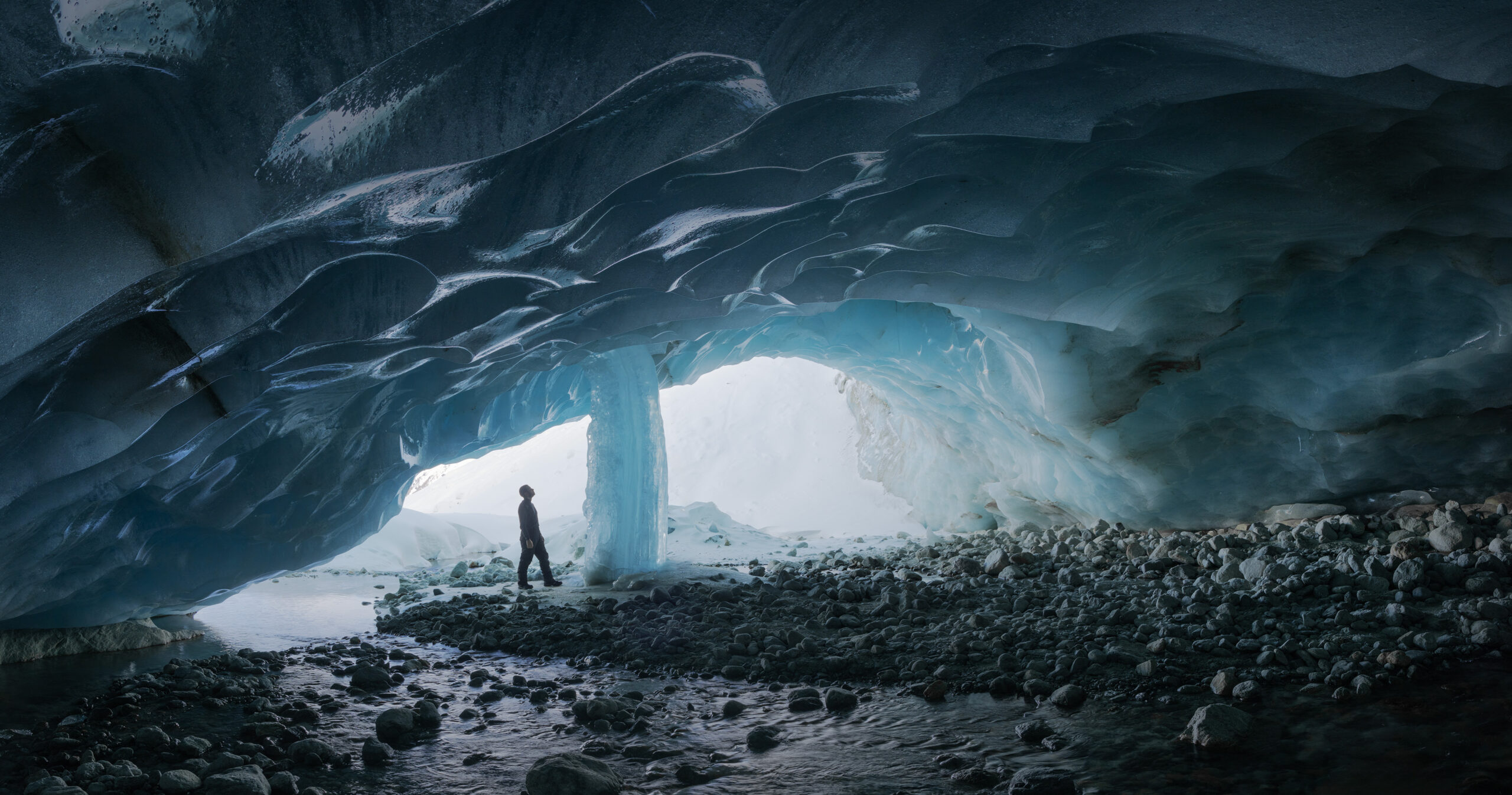 Panoramic view inside the Zinal Glacier ice cave, nestled in the Swiss Alps, captured by photographer Jennifer Esseiva with a Nikon Z8. The image reveals the cave’s sculpted ice walls, layered textures, and the ethereal blue light that defines this majestic natural wonder in Valais, Switzerland.
