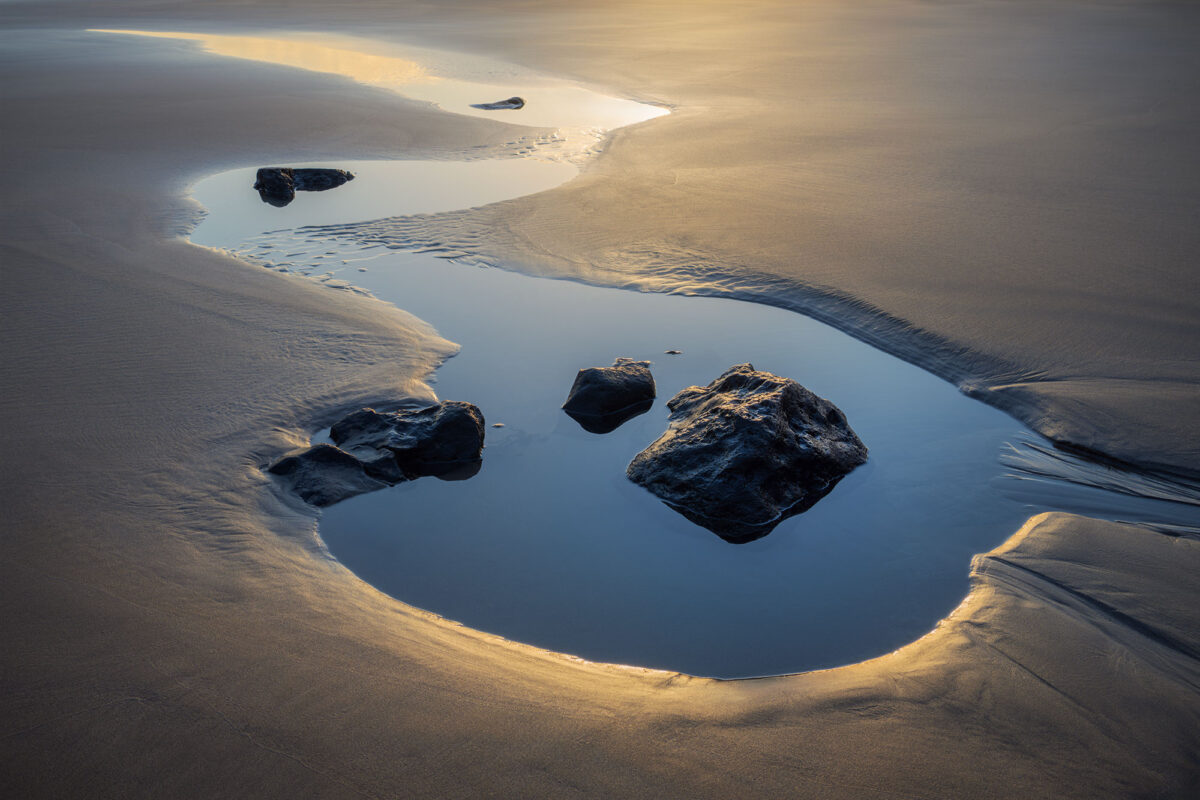 Orzola beach in northern Lanzarote, close-up water detail after low tide in the Canary Islands, showing textures in the wet sand and gentle coastal reflections.