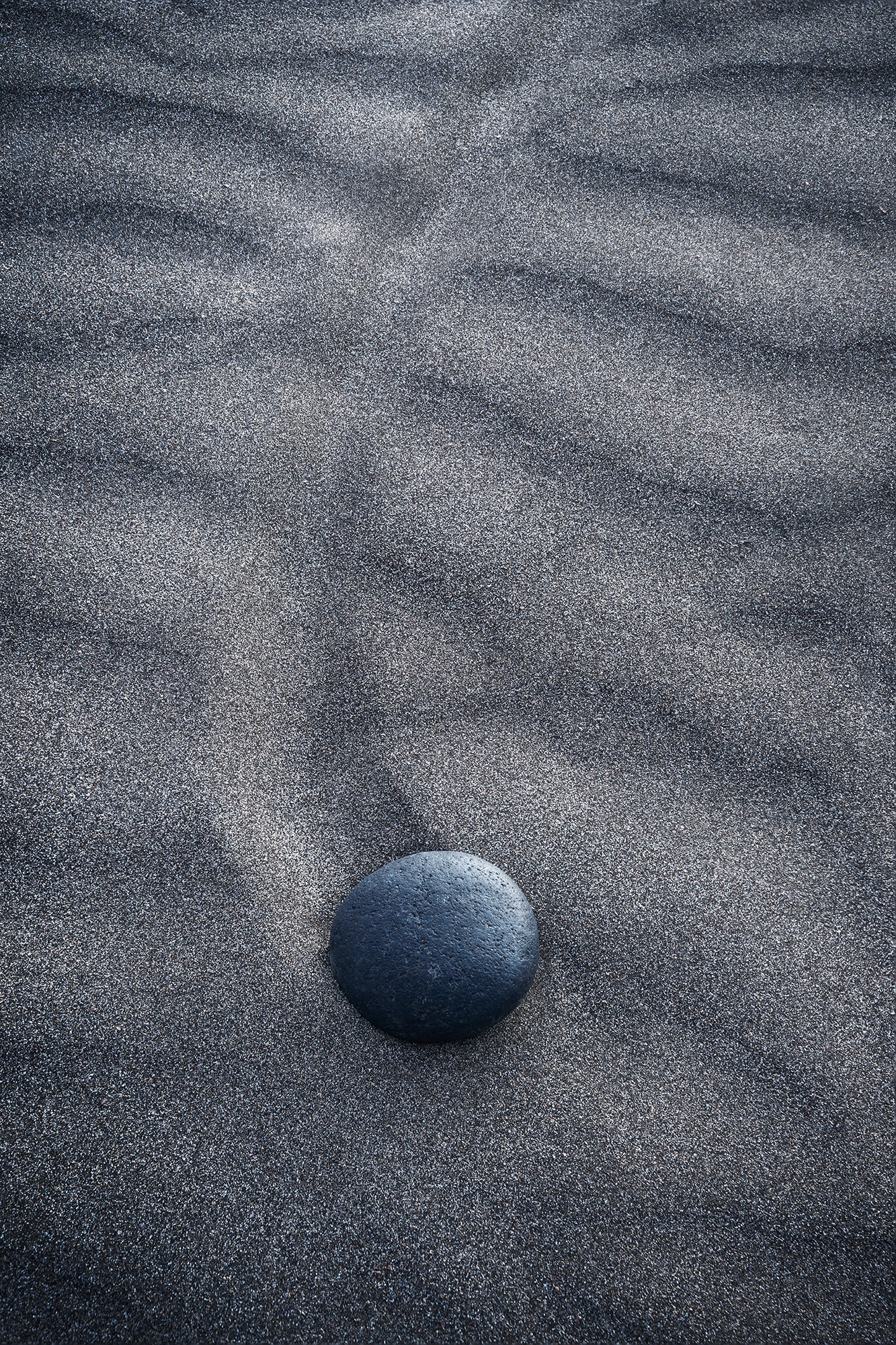 Abstract close-up of small black volcanic stones on the dark sand of Famara Beach in Lanzarote, Canary Islands.