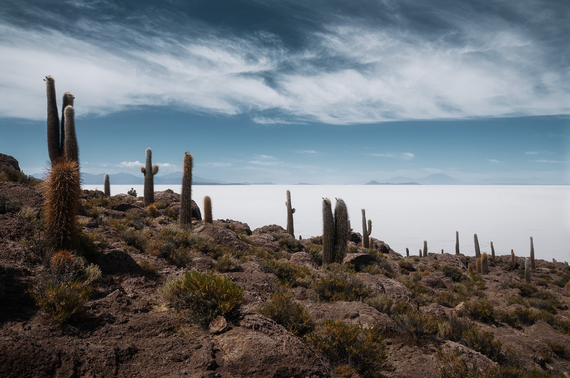 Landscape photograph of Salar de Uyuni in Bolivia, captured from Incahuasi Island, showing the infinite white salt flats under the South American sky.