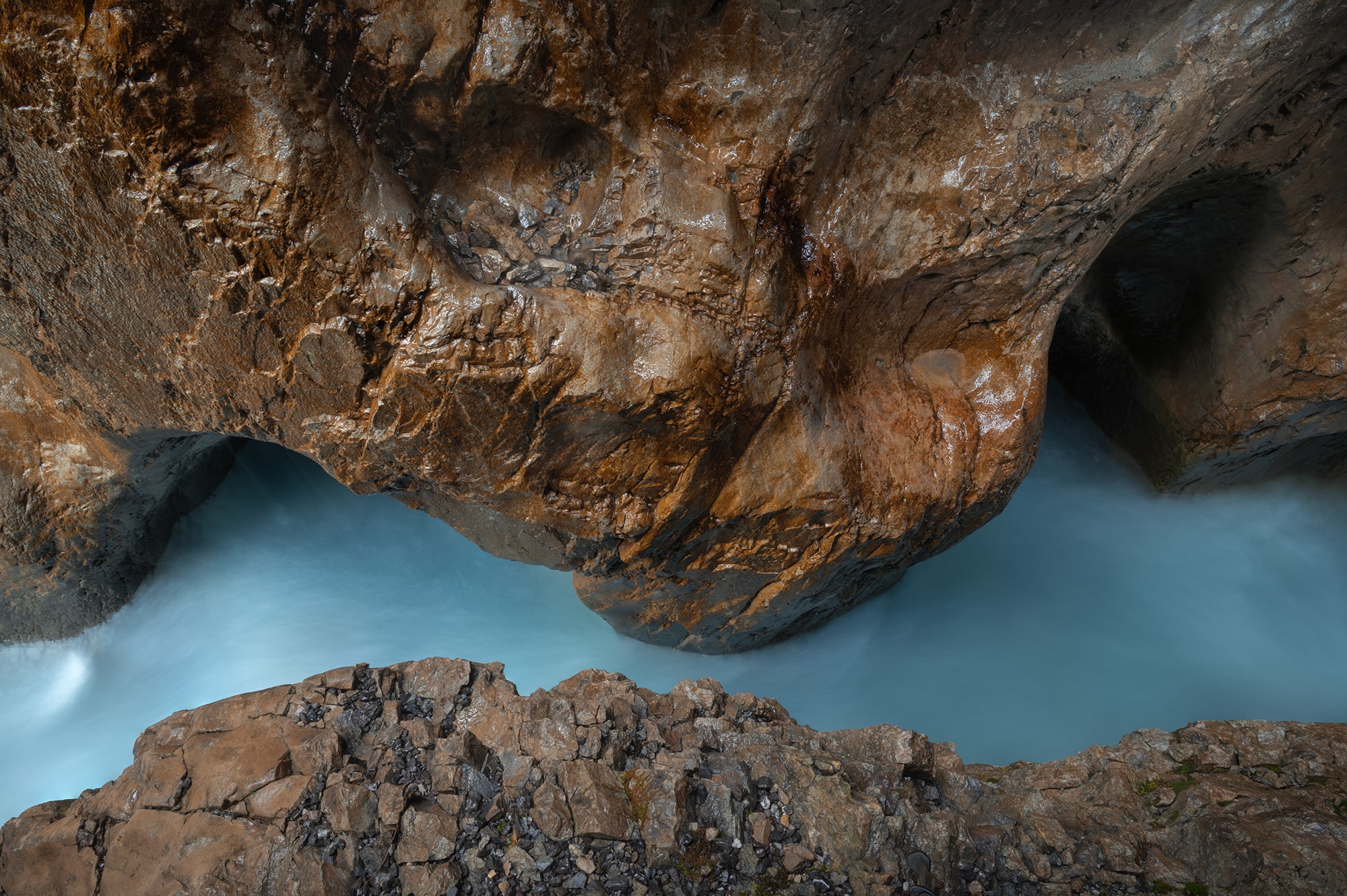 Long exposure landscape photograph of the Rosenlaui Gorge in the Bernese Oberland, Switzerland, with glacier-fed turquoise water contrasting against warm orange rocks.