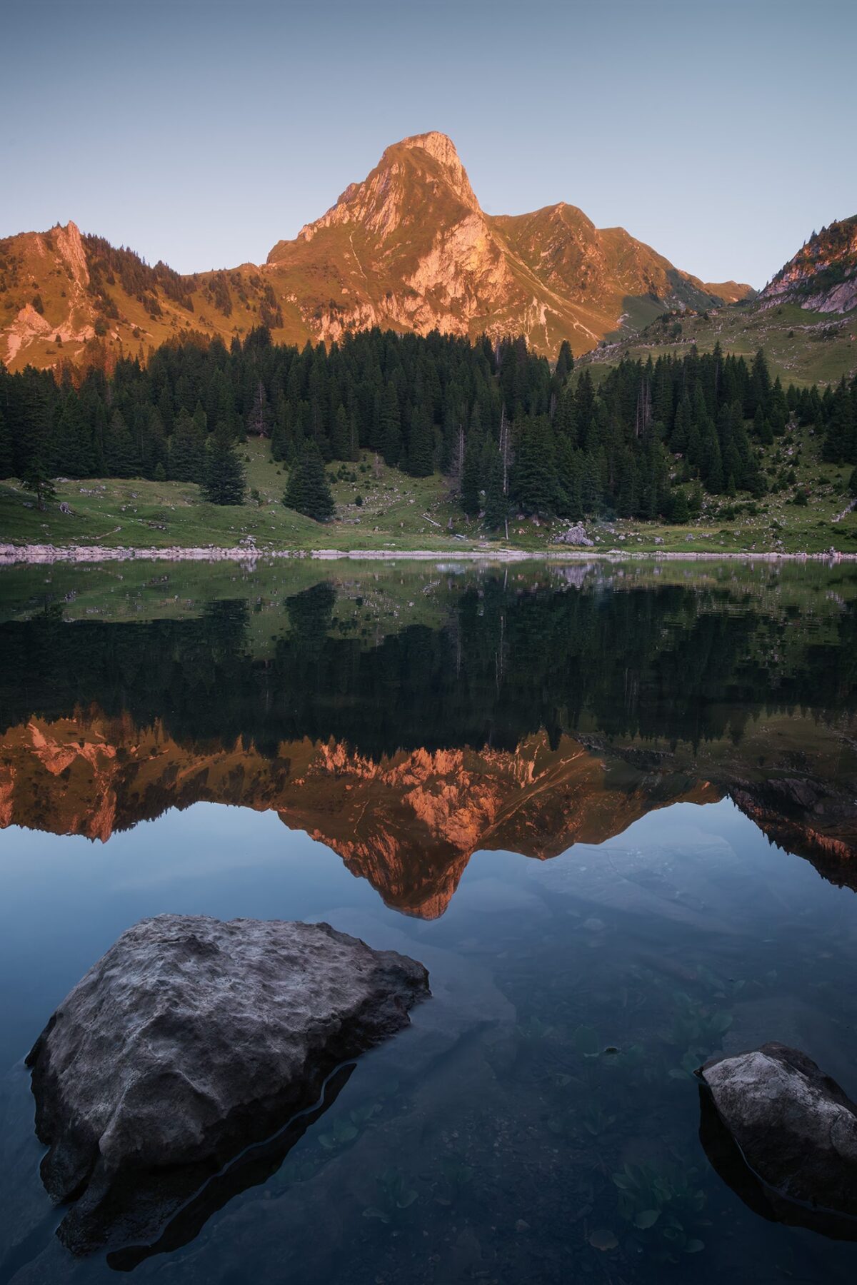 Landscape photography of the Gantrischseeli at sunset, a small alpine lake in the Gantrisch Nature Park in Switzerland, reflecting the surrounding mountains and evening colors.