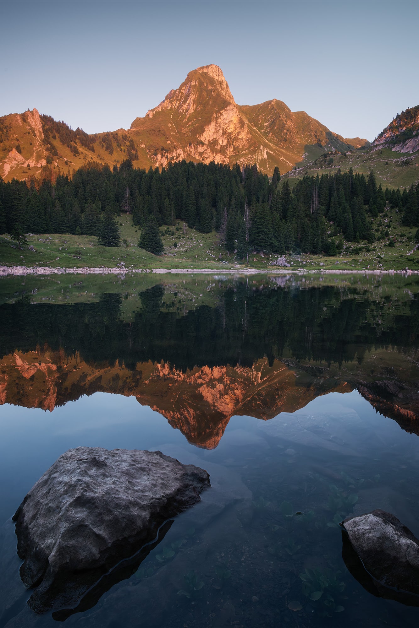 Landscape photography of the Gantrischseeli at sunset, a small alpine lake in the Gantrisch Nature Park in Switzerland, reflecting the surrounding mountains and evening colors.