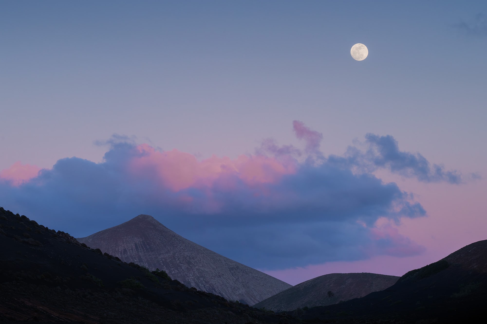 Landscape photography of the moon rise at blue hour near Volcán del Cuervo in Lanzarote, highlighting volcanic terrain and serene twilight colors in the Canary Islands.