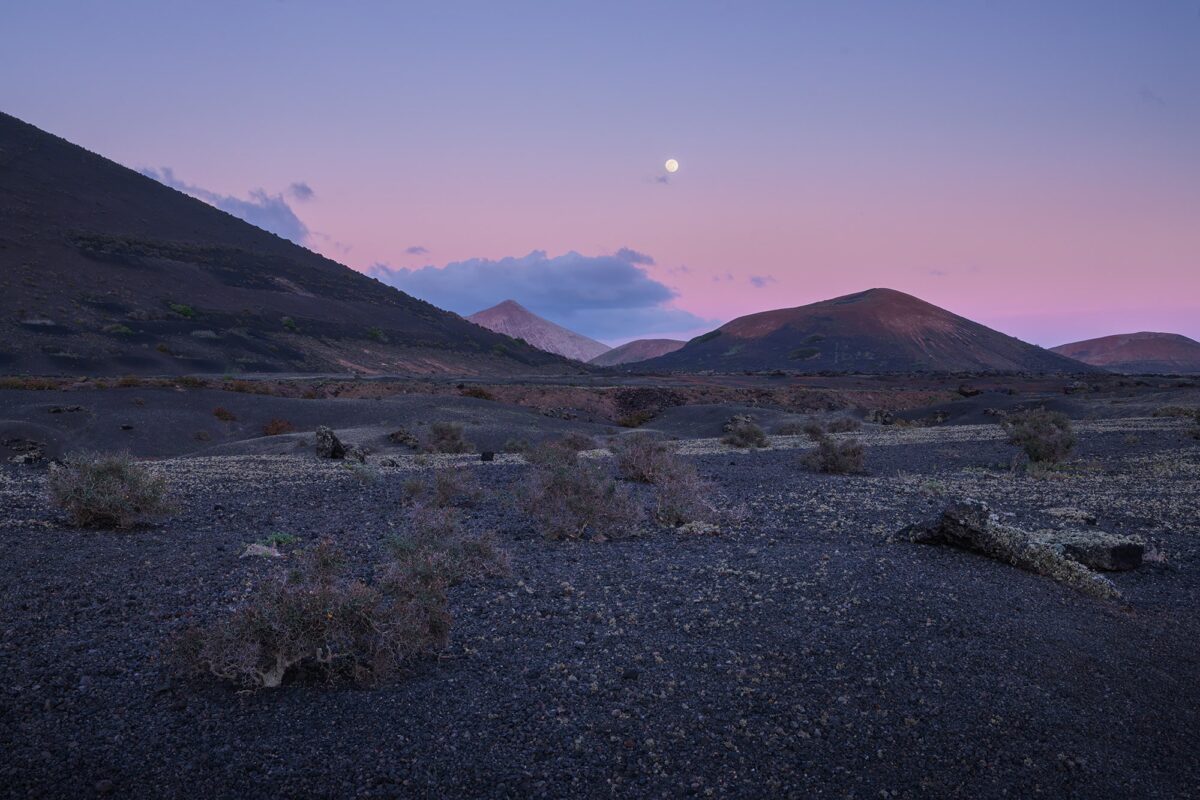 Wide-angle landscape photography of the moon rise at blue hour near Volcán del Cuervo in Lanzarote, showcasing volcanic landscapes and soft twilight hues in the Canary Islands.