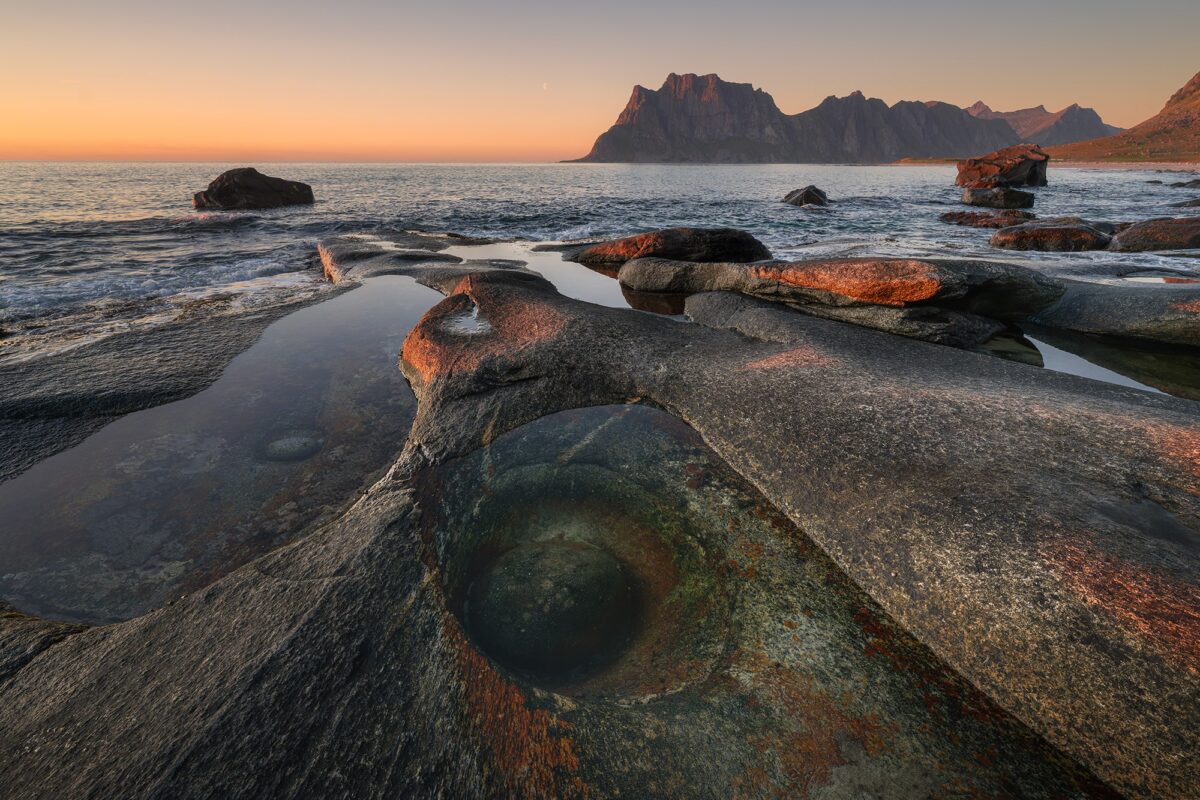 Landscape photography of the Dragon Eye rock formation at Uttakleiv Beach, Lofoten Norway, captured at sunset with dramatic light over the Arctic scenery.