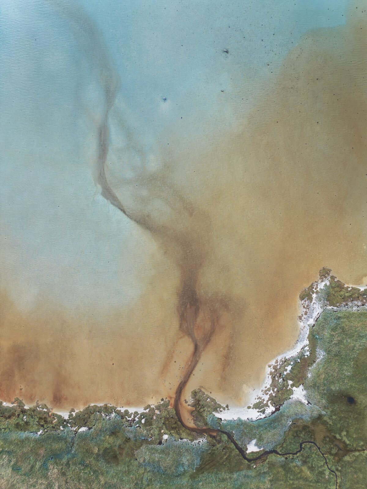 Top-down drone photography of the shoreline in the Steigen region, Norway, showing an underwater river flowing into the sea and creating abstract patterns in the turquoise and sandy coastal waters.