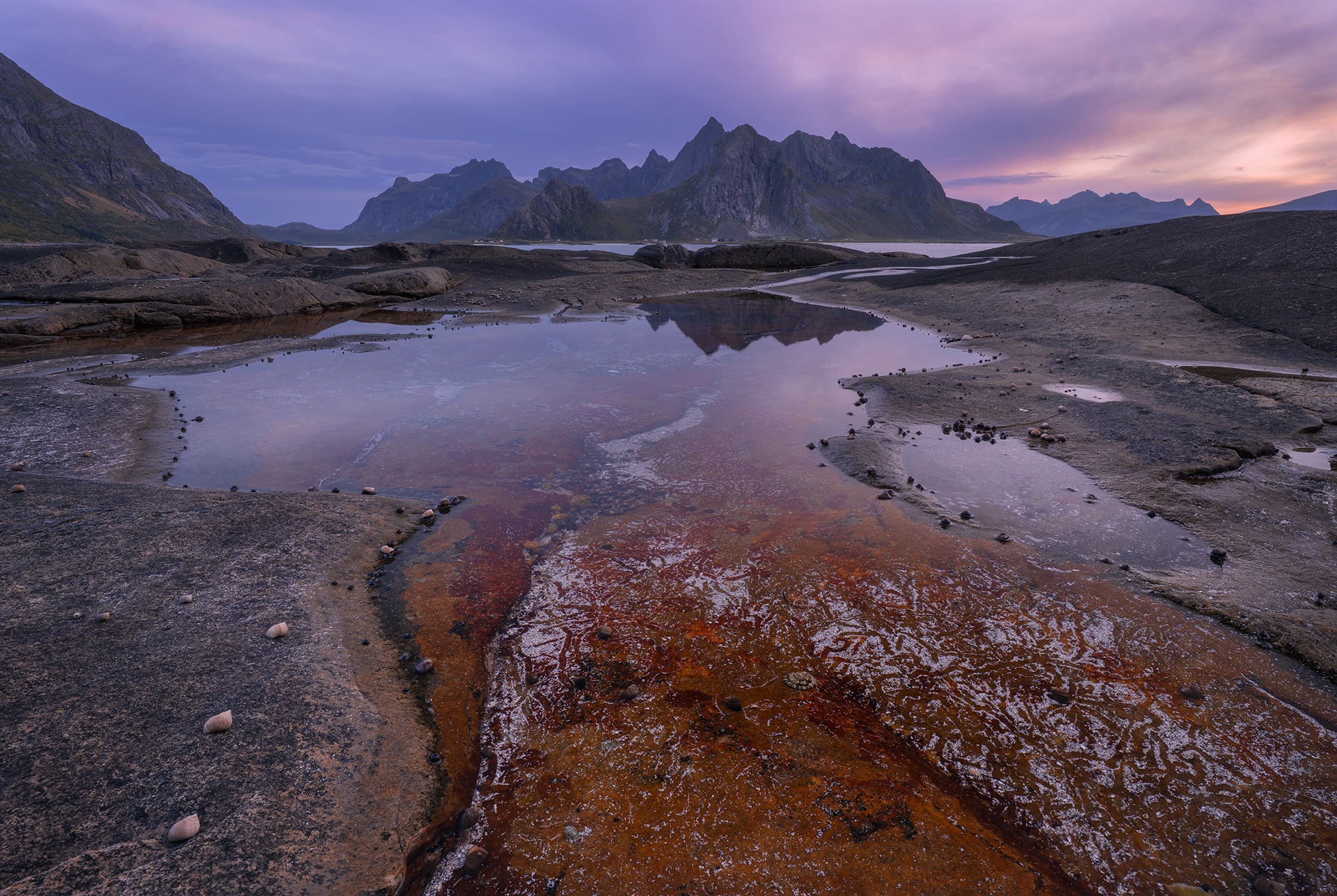 Landscape photography captured with a Nikon Z8 at sunset near Vareid in the Lofoten Islands, Norway, featuring rocky foreground textures and reflections under soft evening light.